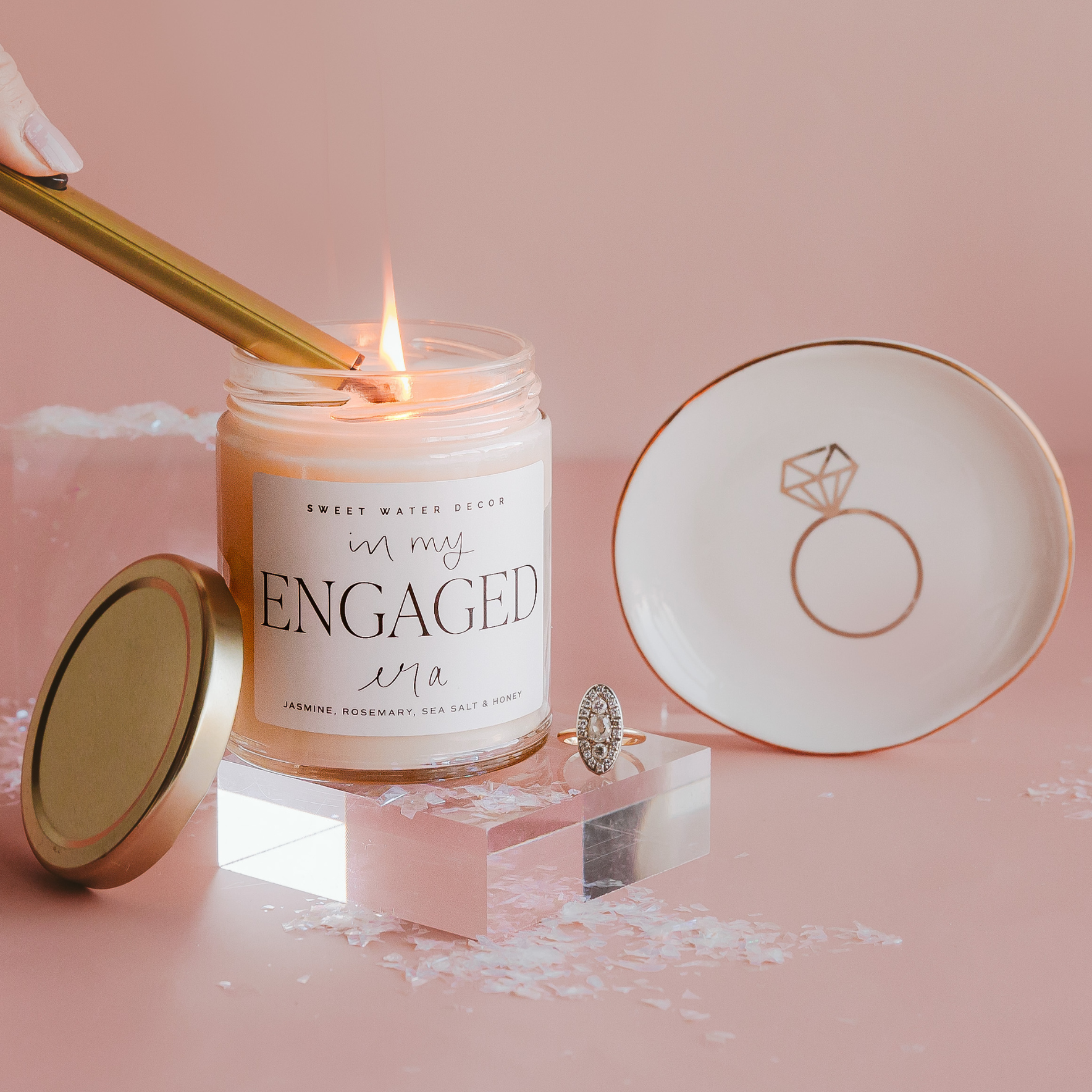 Candle labeled 'In my Engaged Life' with a ring and decorative plate on a pink background