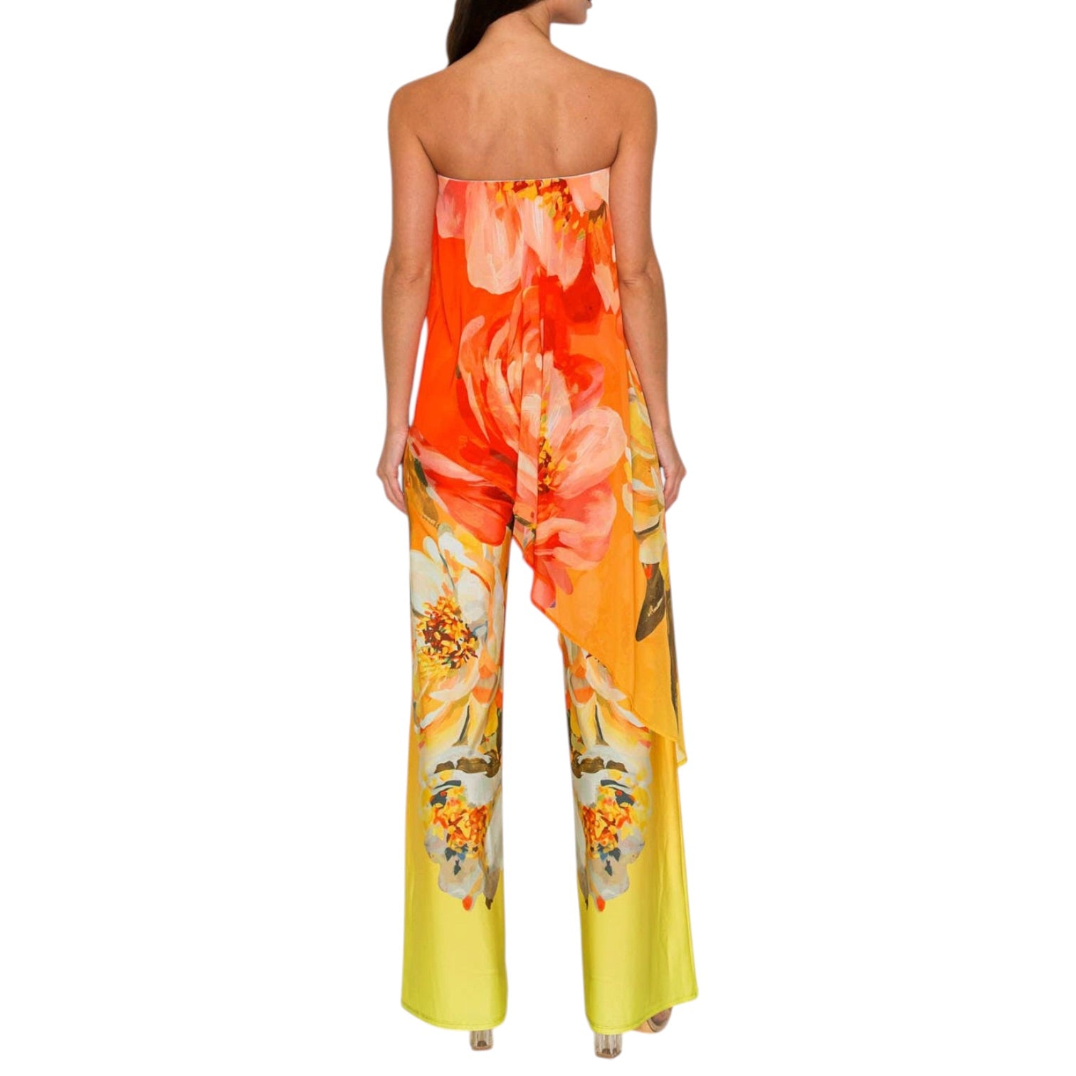 Woman wearing a strapless floral jumpsuit with orange and yellow flowers on a white background