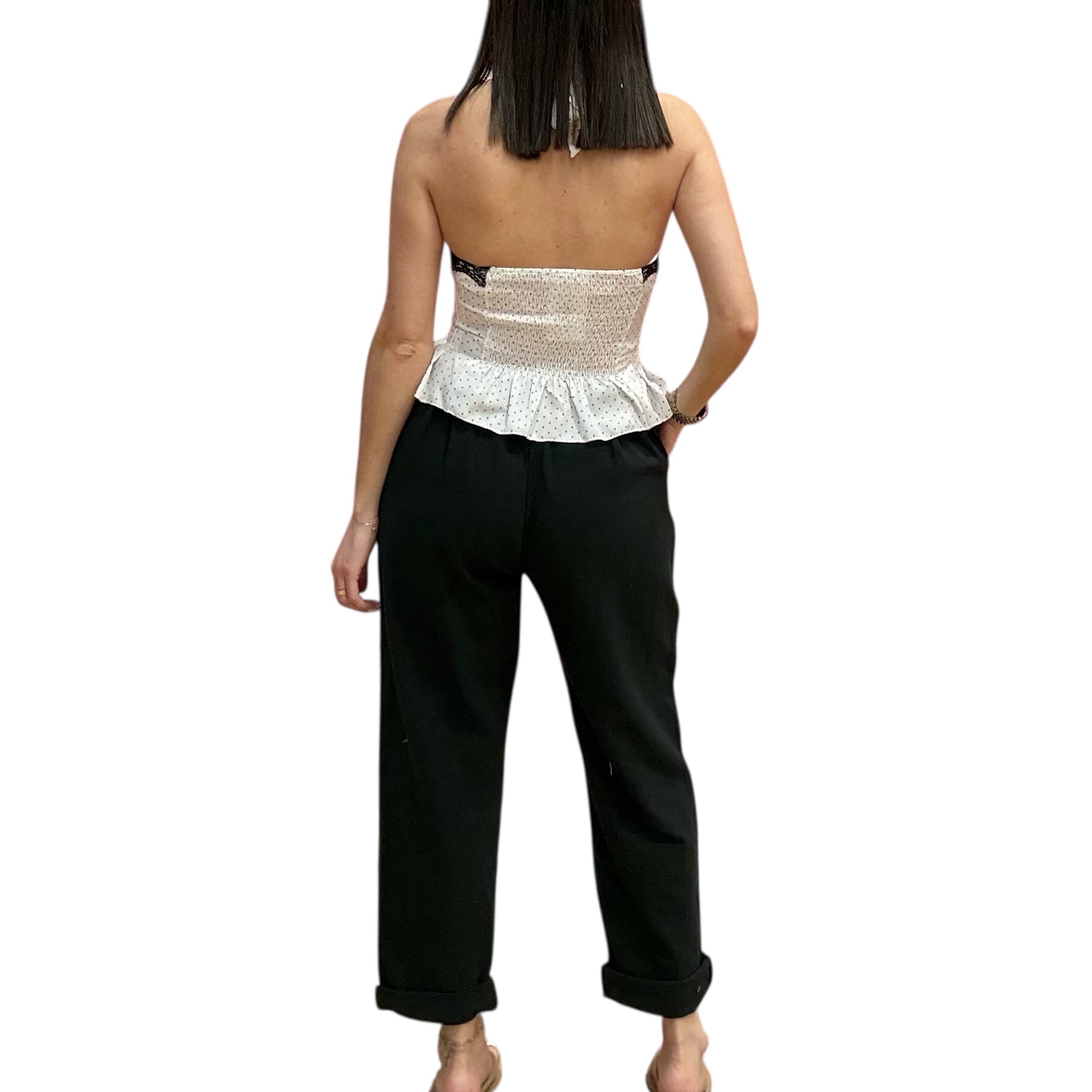 Woman wearing a white peplum top and black pants on a white background