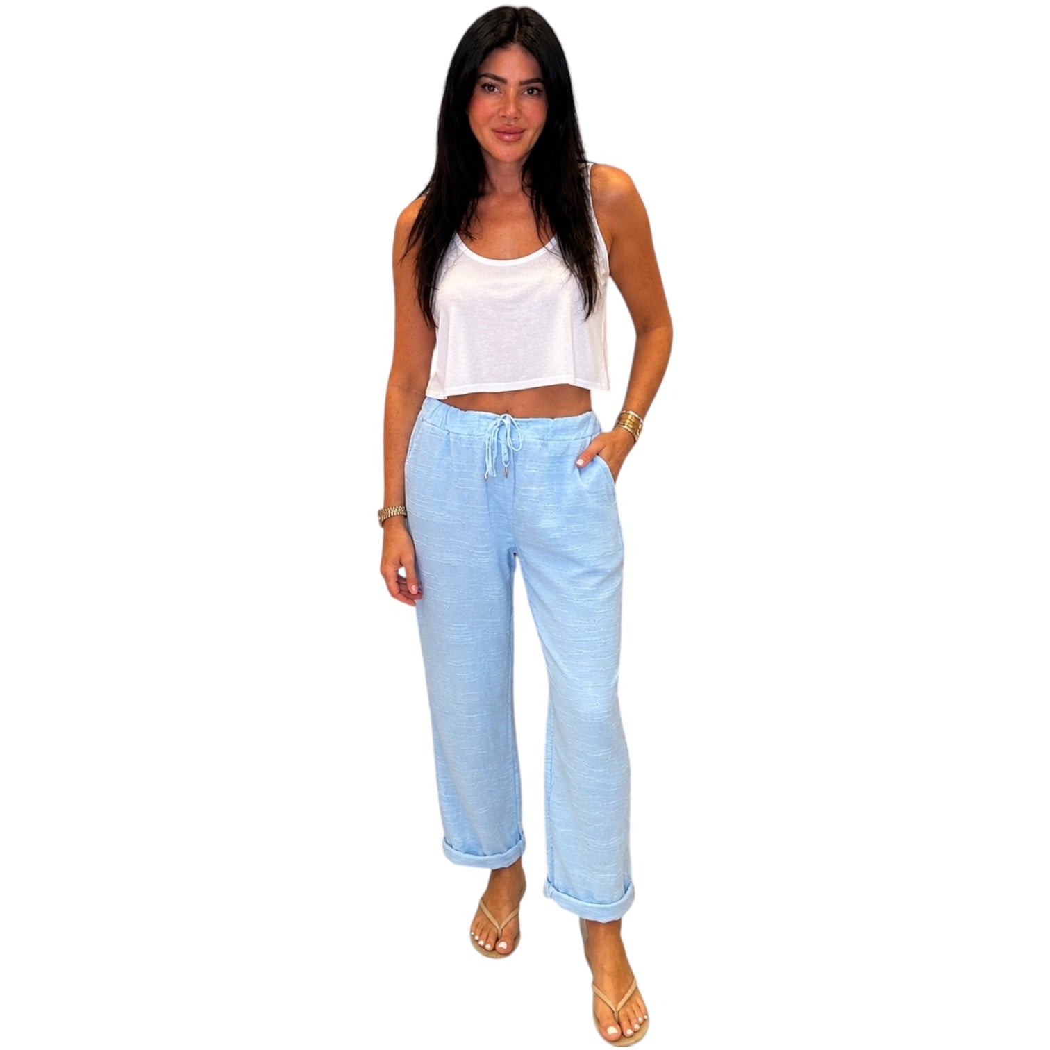 Woman wearing a white tank top and light blue pants on a white background