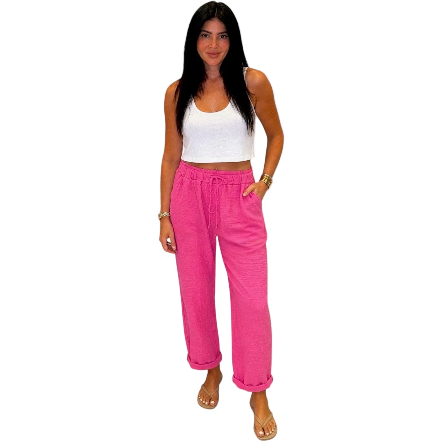 Woman wearing a white top and bright pink pants on a white background