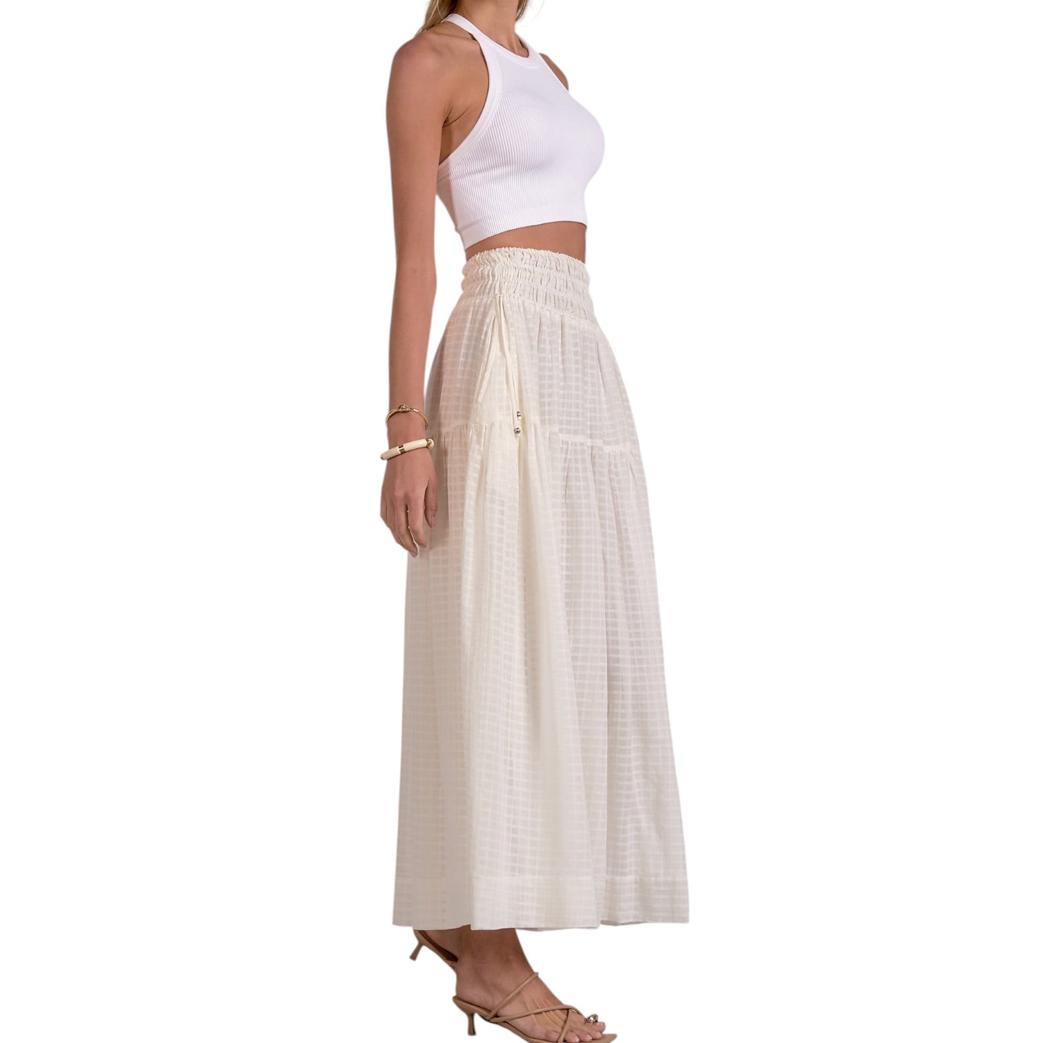 Woman wearing a white sleeveless top and beige checkered skirt on a white background