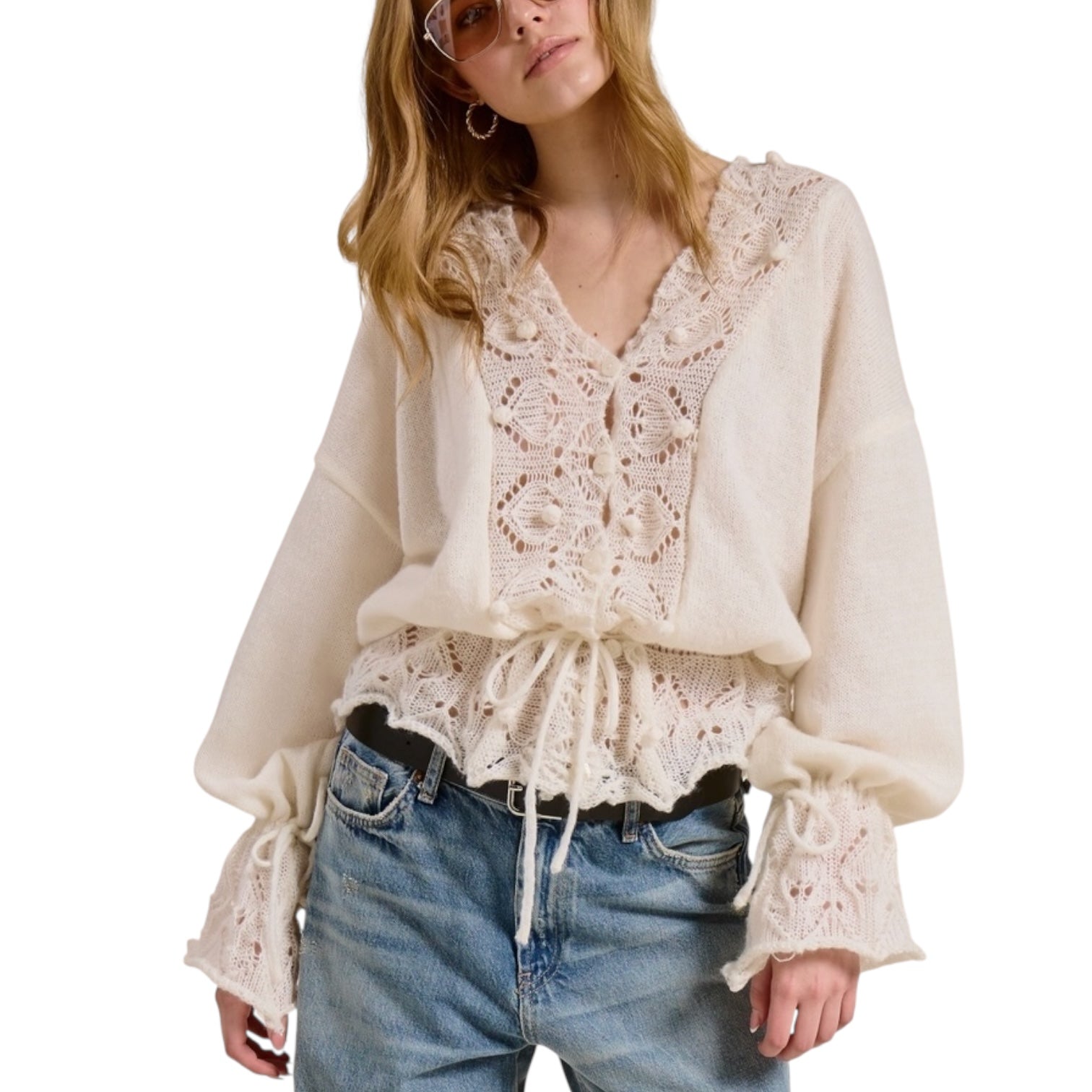 Woman wearing a cream lace blouse and blue jeans on a white background
