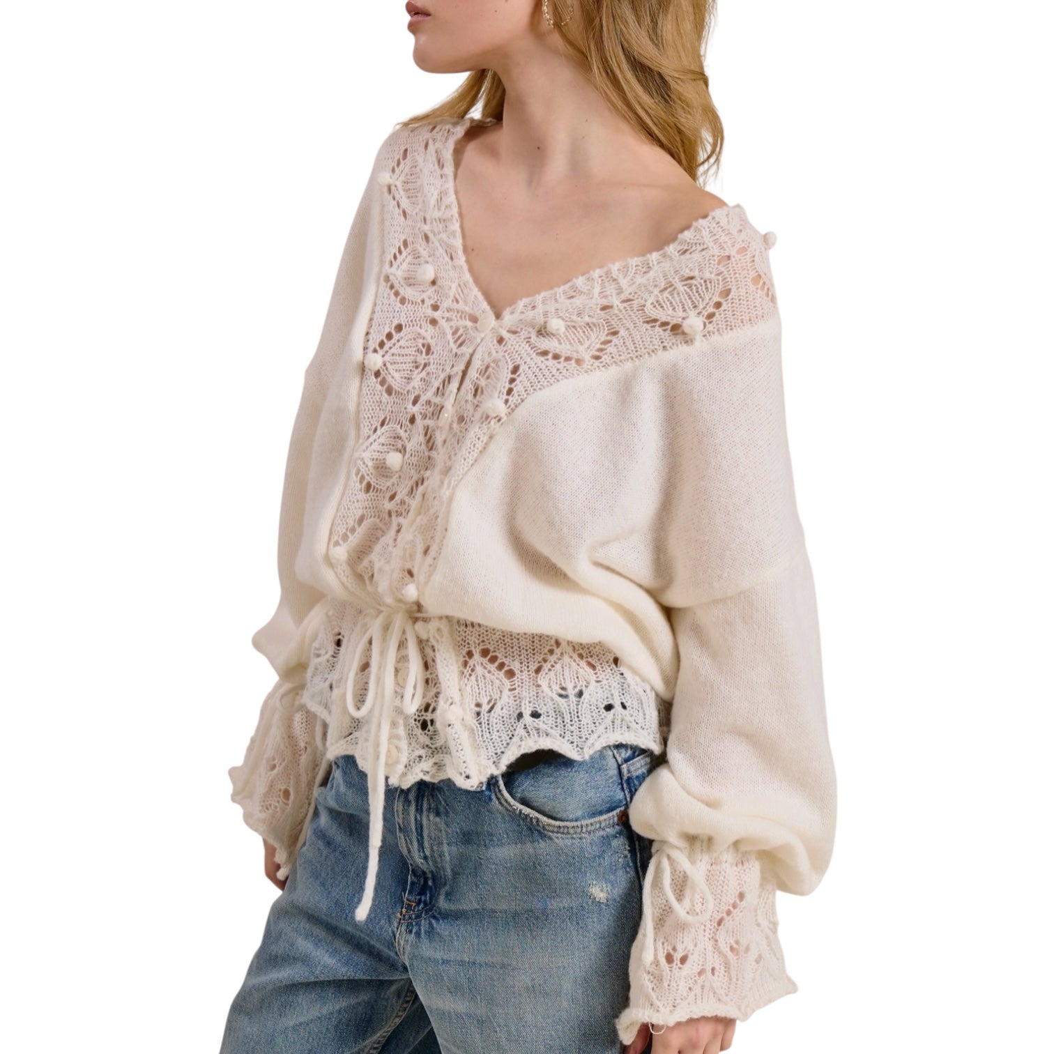 Woman wearing a cream lace top and blue jeans on a white background