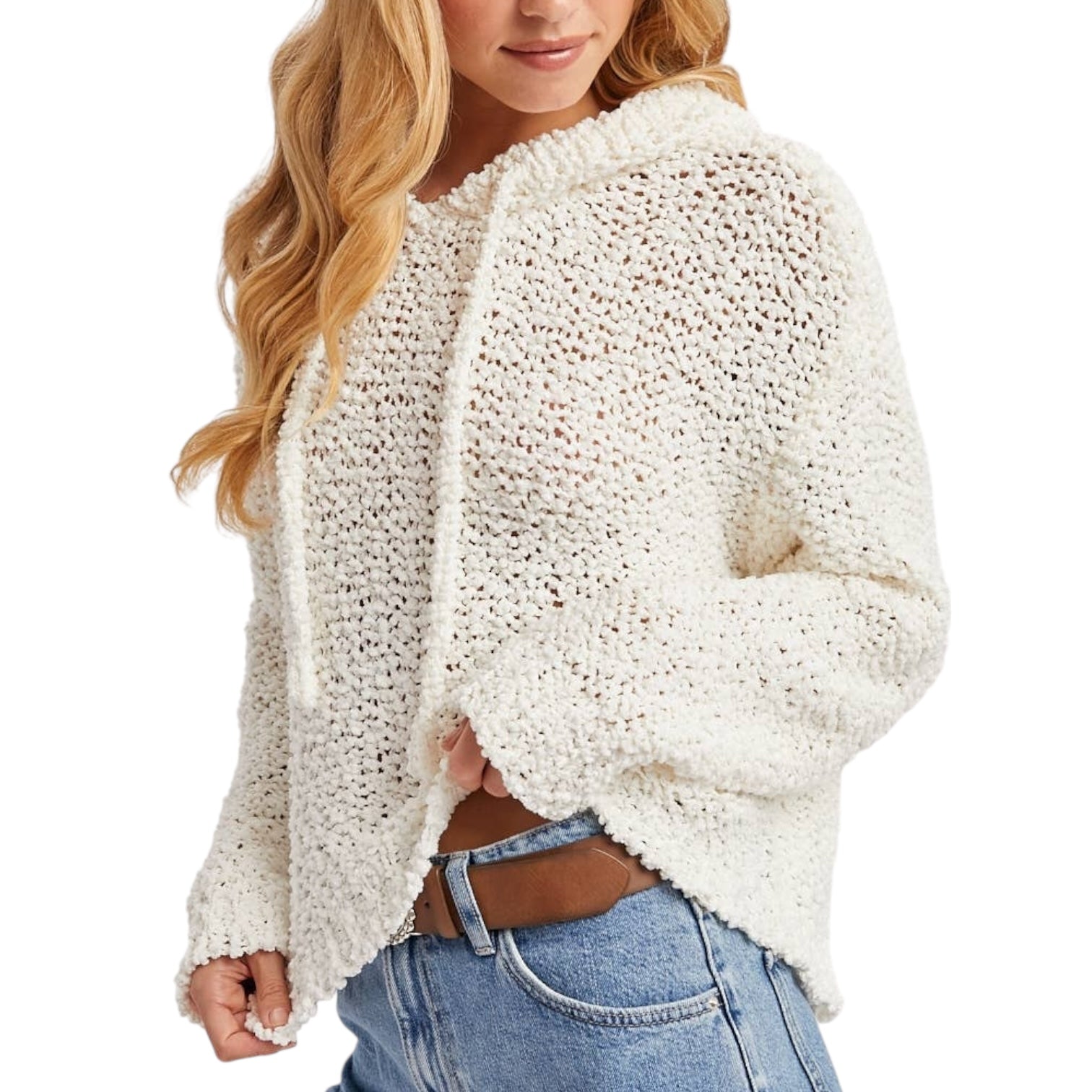 Woman wearing a white chunky knit sweater and blue jeans on a white background