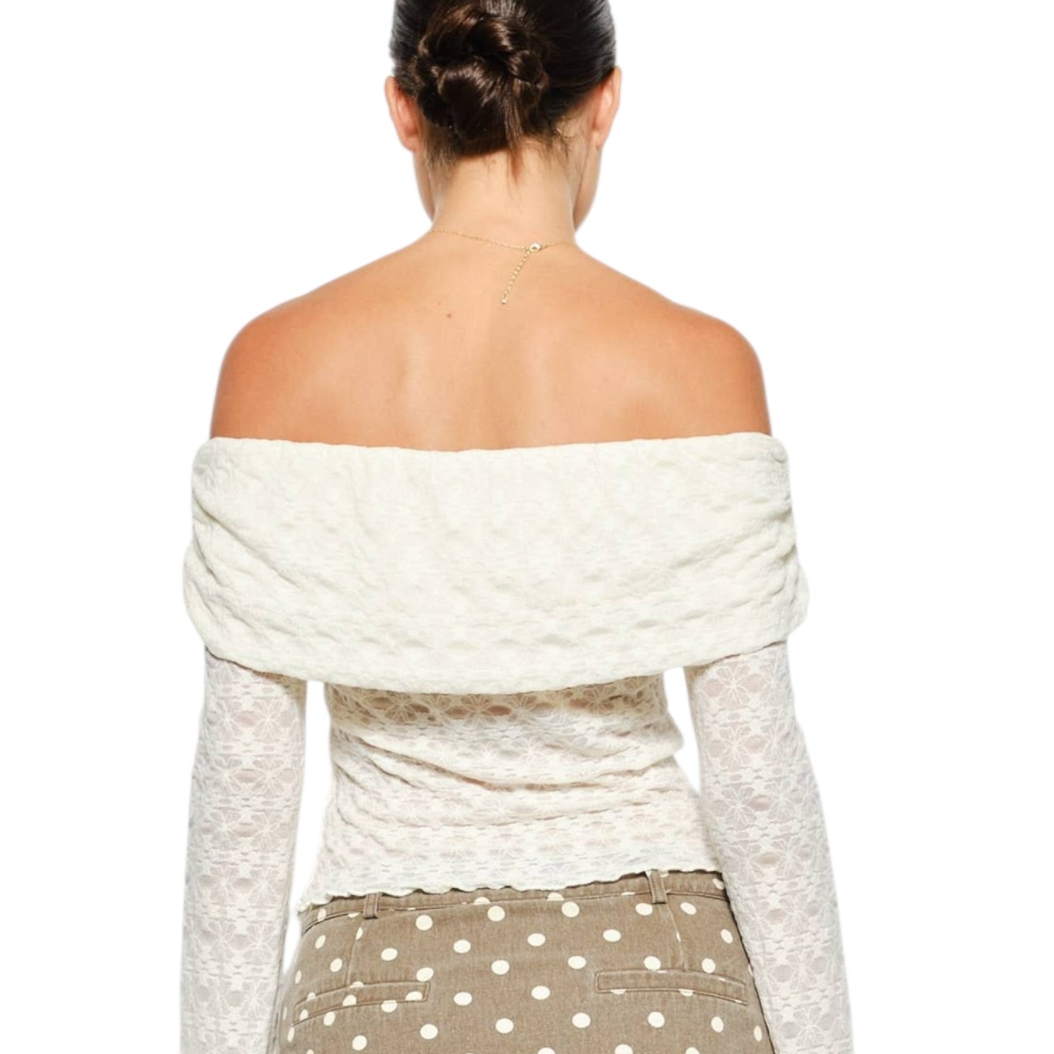 Woman wearing a white off-shoulder top over a gray long-sleeve shirt with polka dot pants on a white background