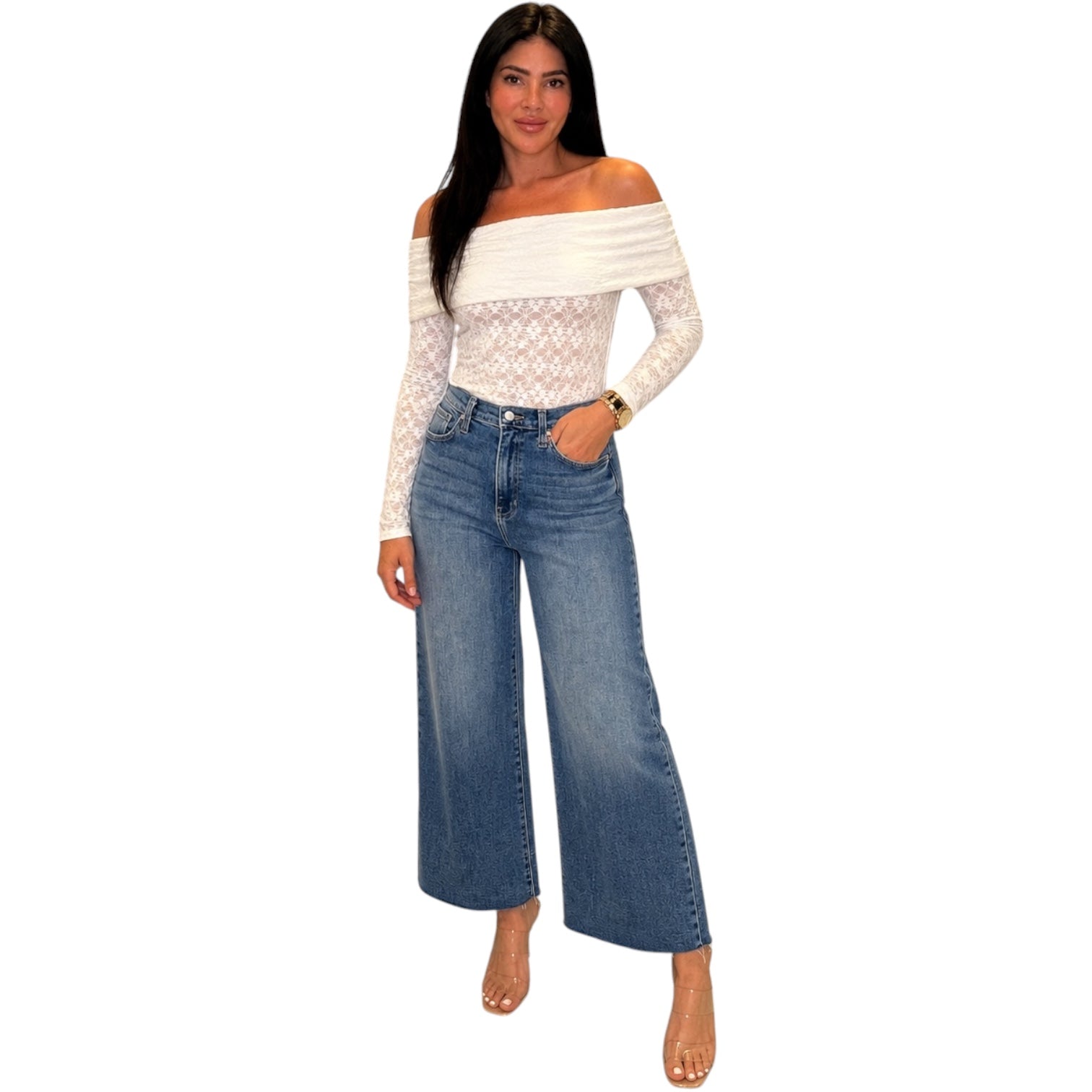 Woman wearing a white off-shoulder top and blue jeans on a white background