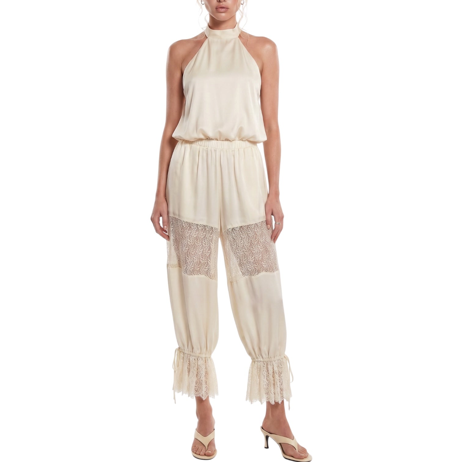 Woman wearing a cream-colored jumpsuit with lace details on a white background