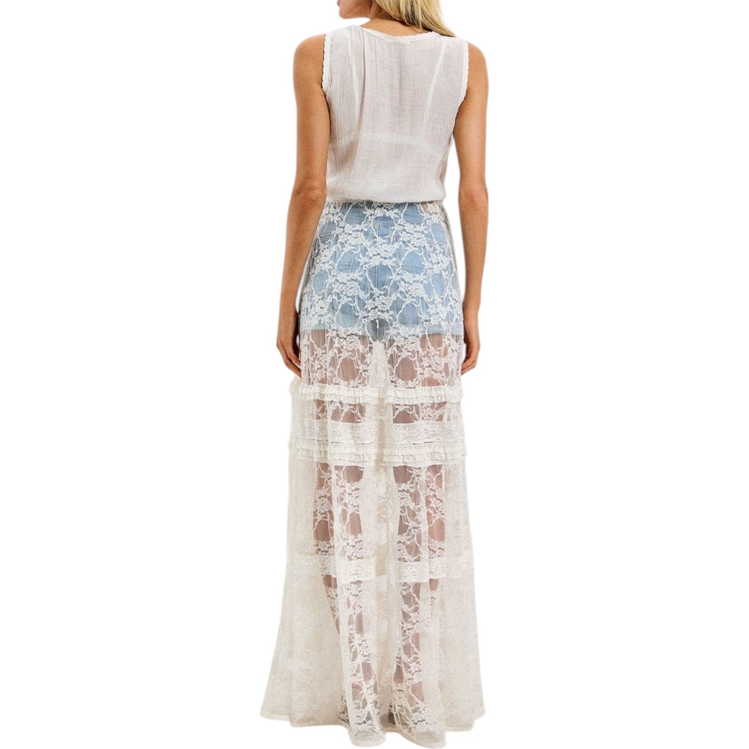 Woman wearing a ivory lace cover-up with denim shorts underneath on a white background