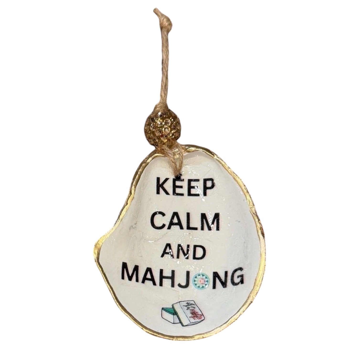 An irregular-shaped white ornament with a gold-colored edge, featuring the text 'KEEP CALM AND MAHJONG' in black, with a small mahjong tile illustration at the bottom and a hanging loop at the top.