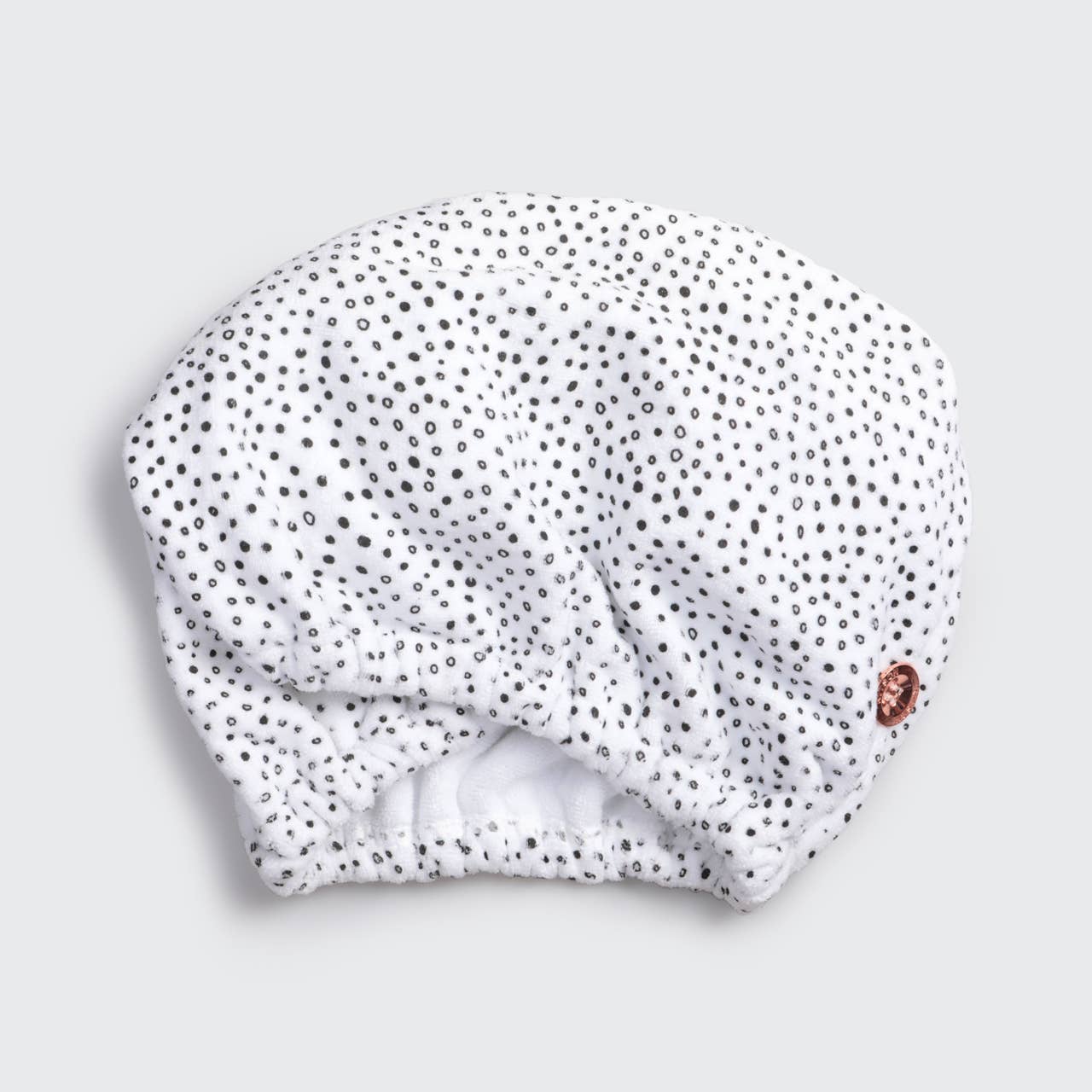 White hair towel with black polka dots on a light gray background