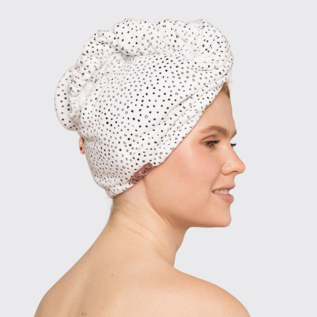 Woman wearing a white shower cap with black polka dots on a light gray background