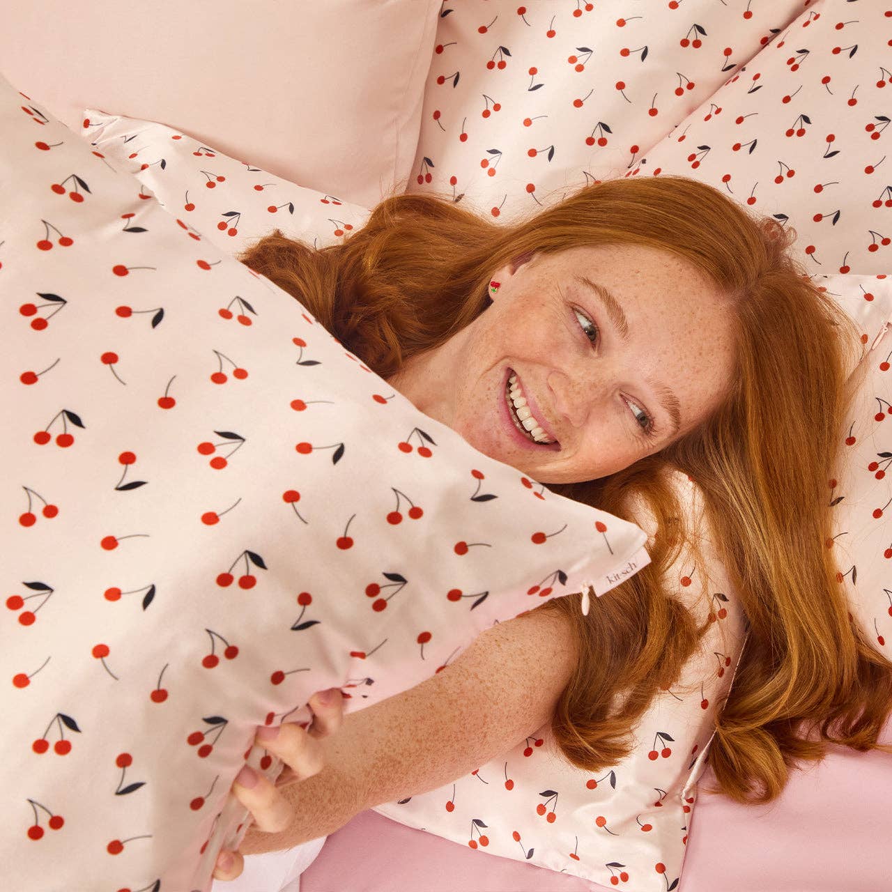 Woman lying on a bed with cherry-patterned bedding
