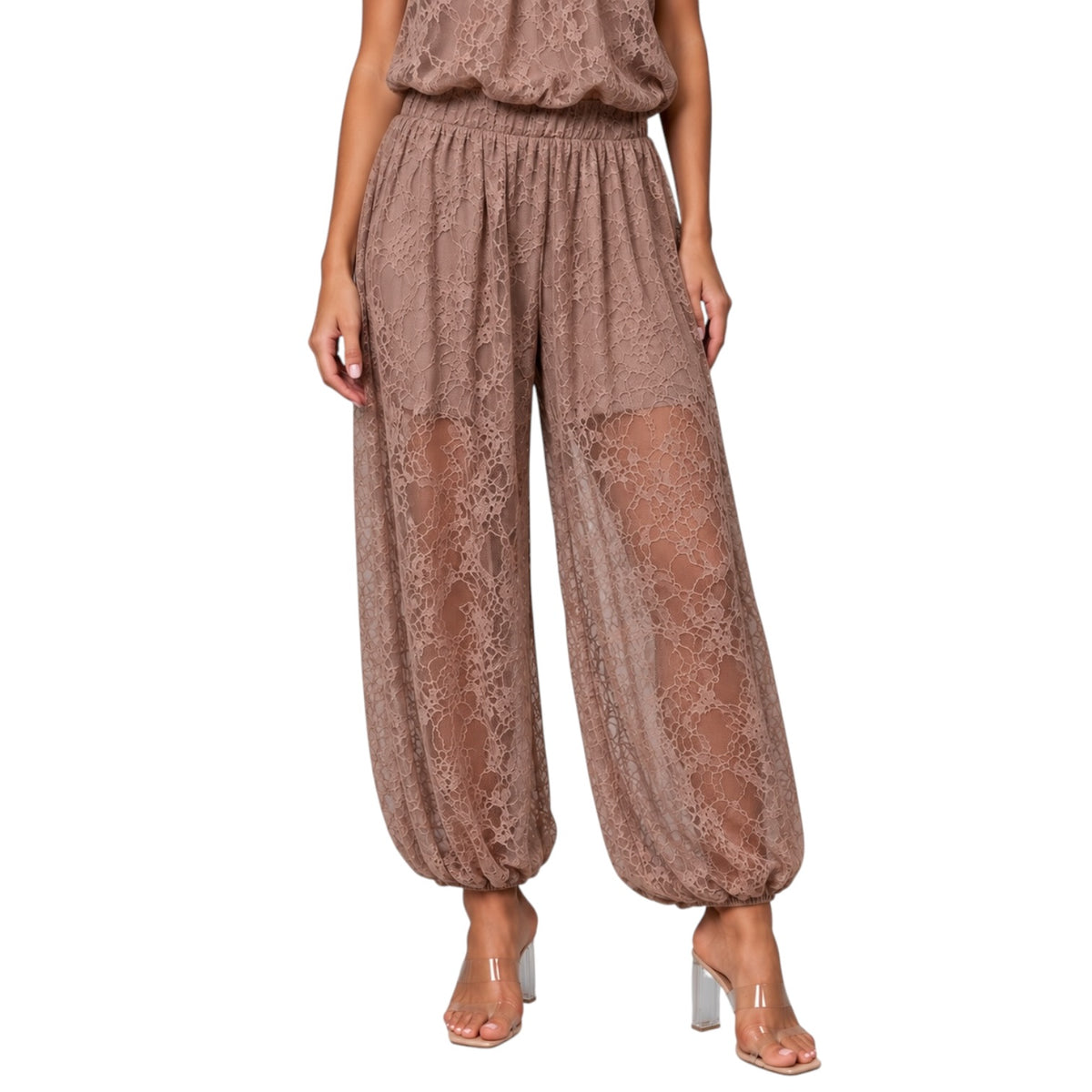 A model wearing loose, wide-leg lace harem pants in a dusty mauve-brown color, paired with clear high-heeled sandals, shown against a plain white background.