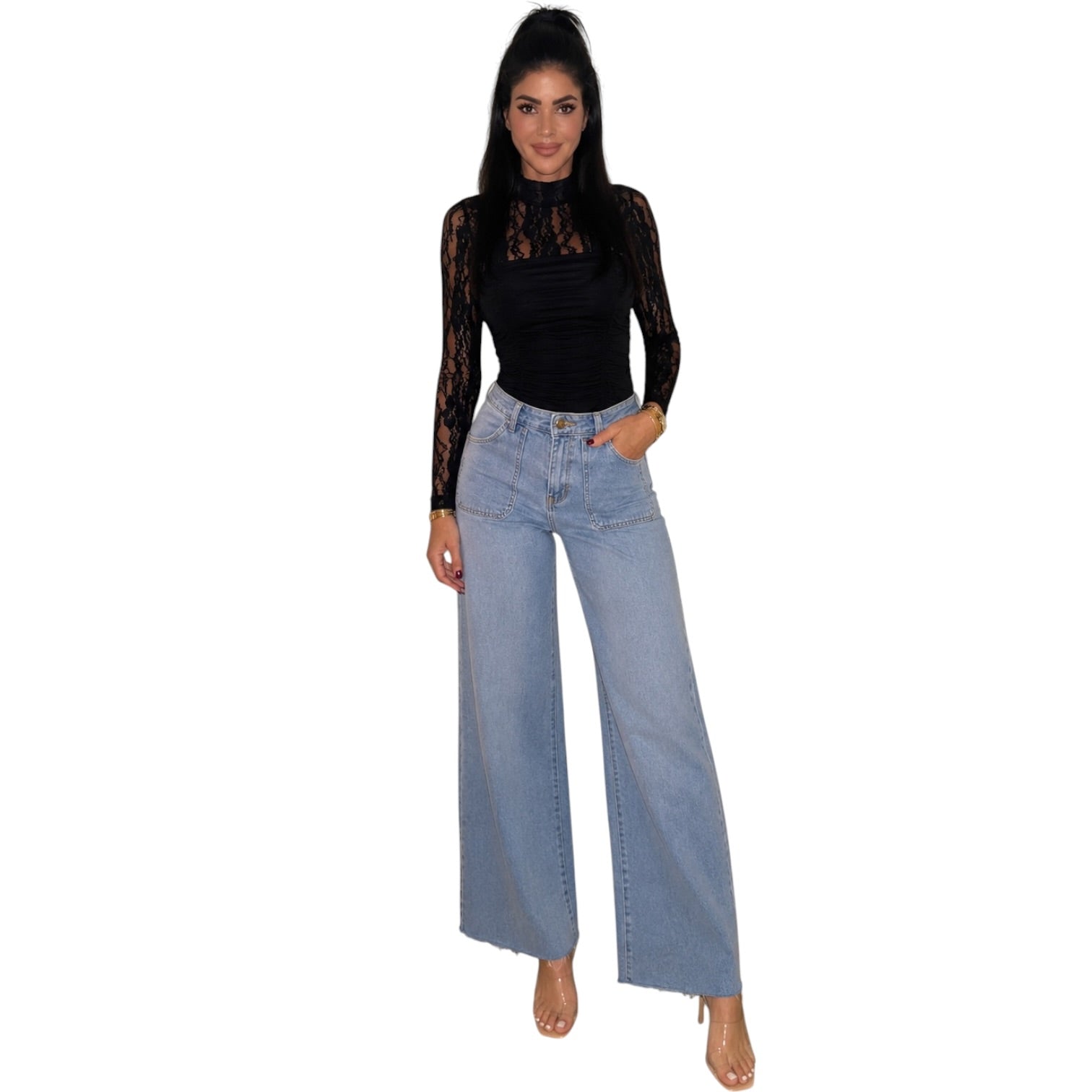 A woman modeling a black long-sleeve lace top and light-wash wide-leg denim jeans against a plain white background.
