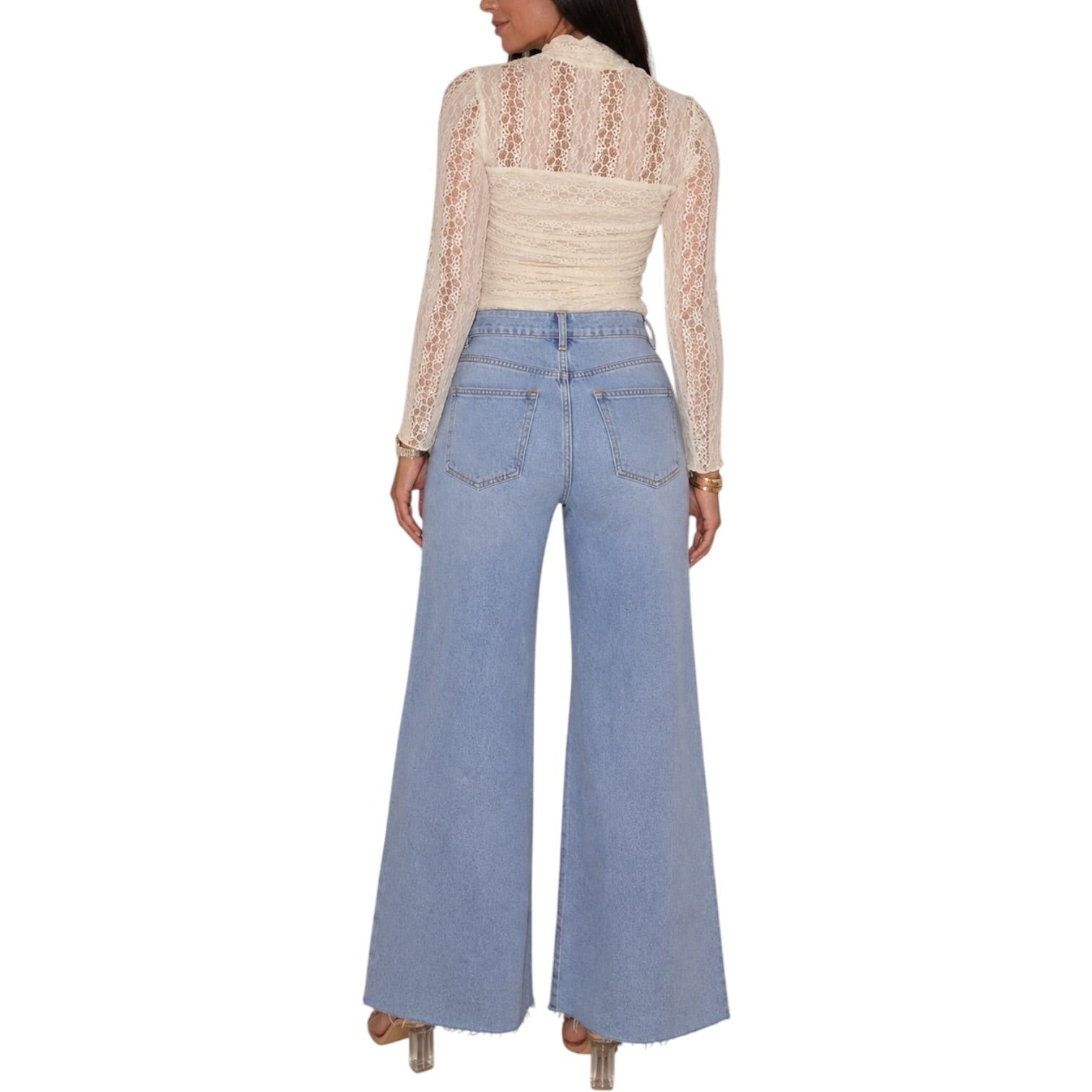A model shown from the back wearing a cream lace long-sleeve top and light blue wide-leg denim jeans against a plain white background.