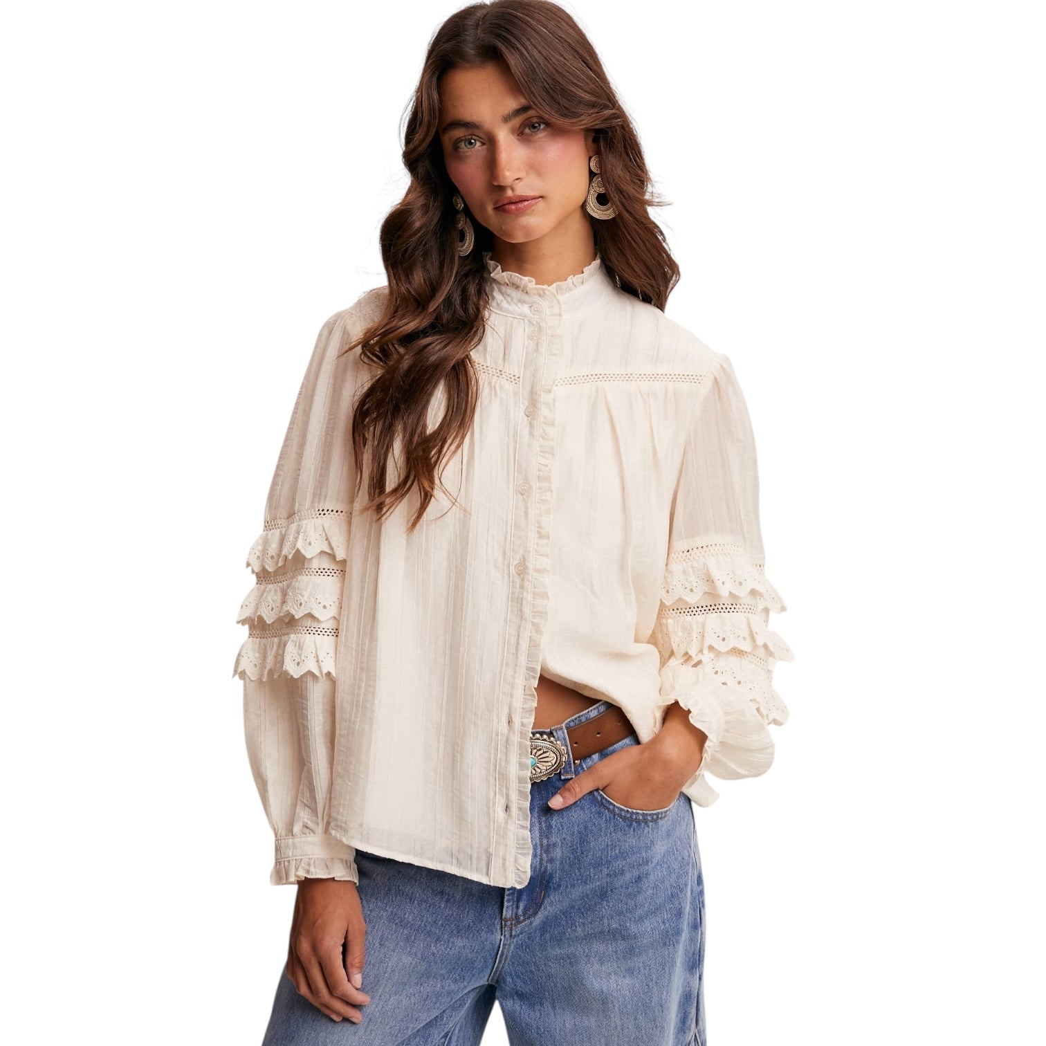 Woman wearing a white blouse with ruffled details and blue jeans on a white background