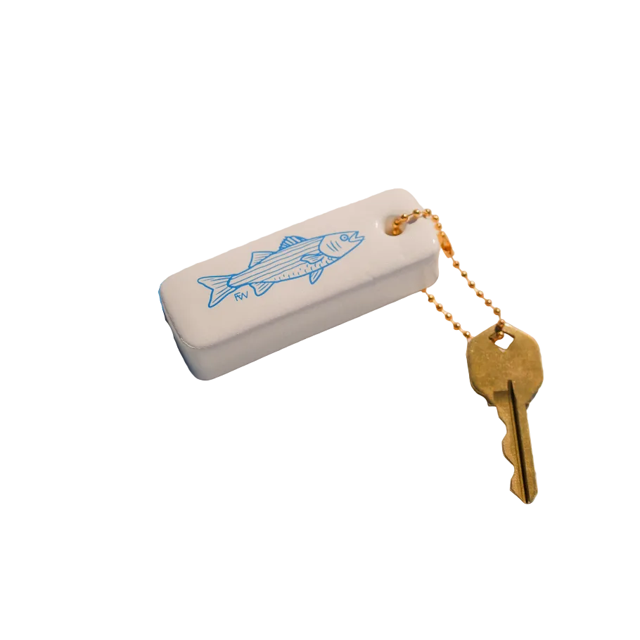 White device with blue fish design, blue rope, and gold key on a textured beige surface