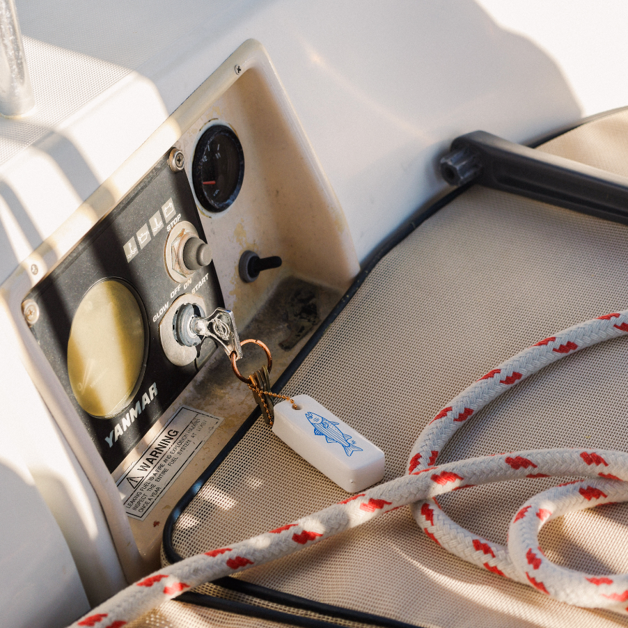 Close-up of a boat's control panel with a rope and keychain on a white surface.