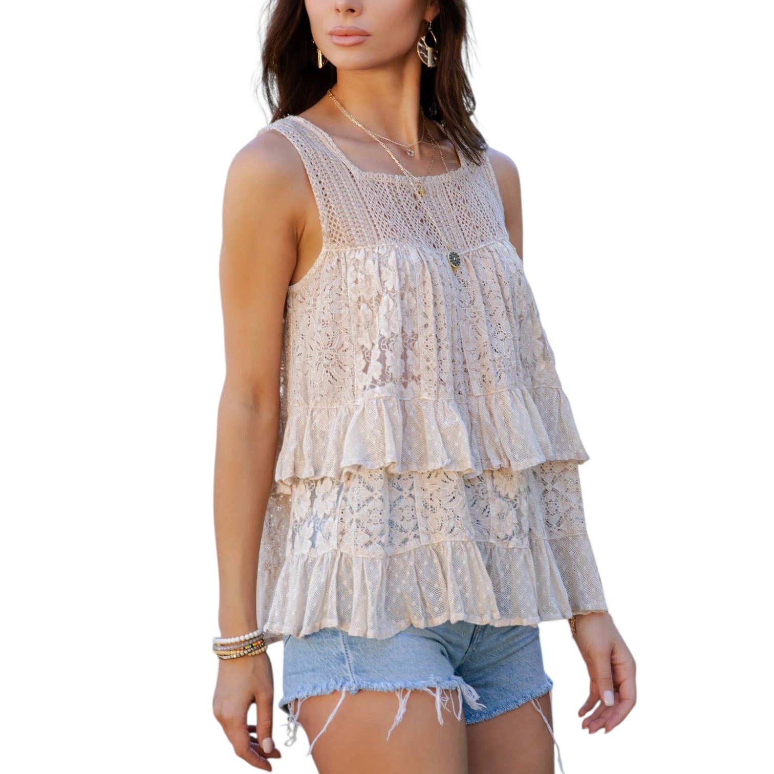 Woman wearing a layered lace top and denim shorts on a white background
