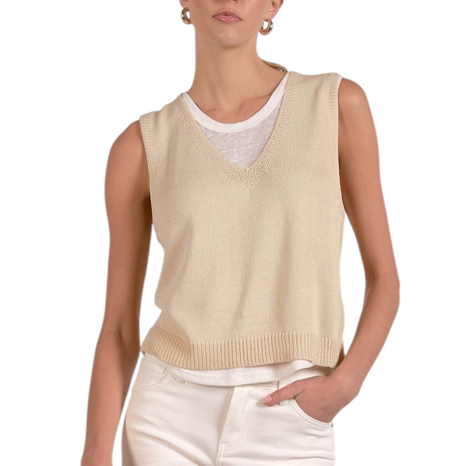 Woman wearing a beige sleeveless sweater over a white shirt on a white background