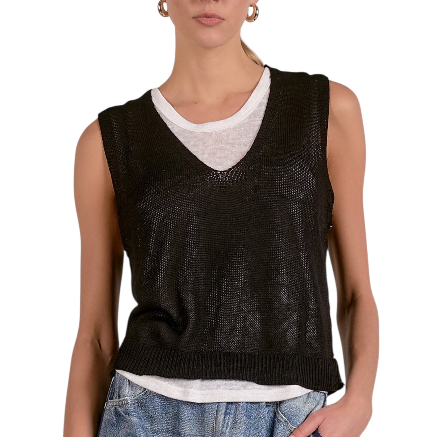 Person wearing a black sleeveless knitted top over a white shirt with a white background
