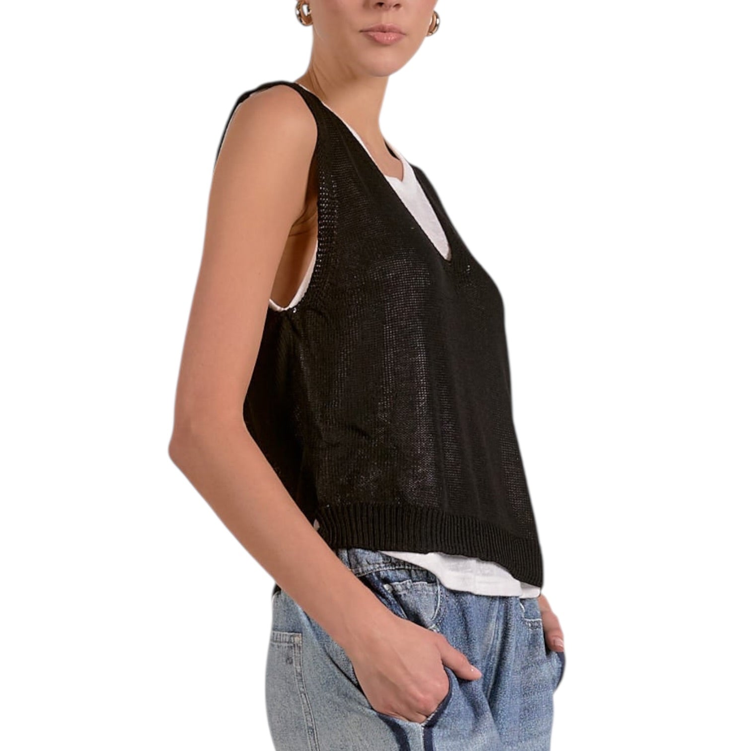 Person wearing a black sleeveless sweater over a white shirt on a white background