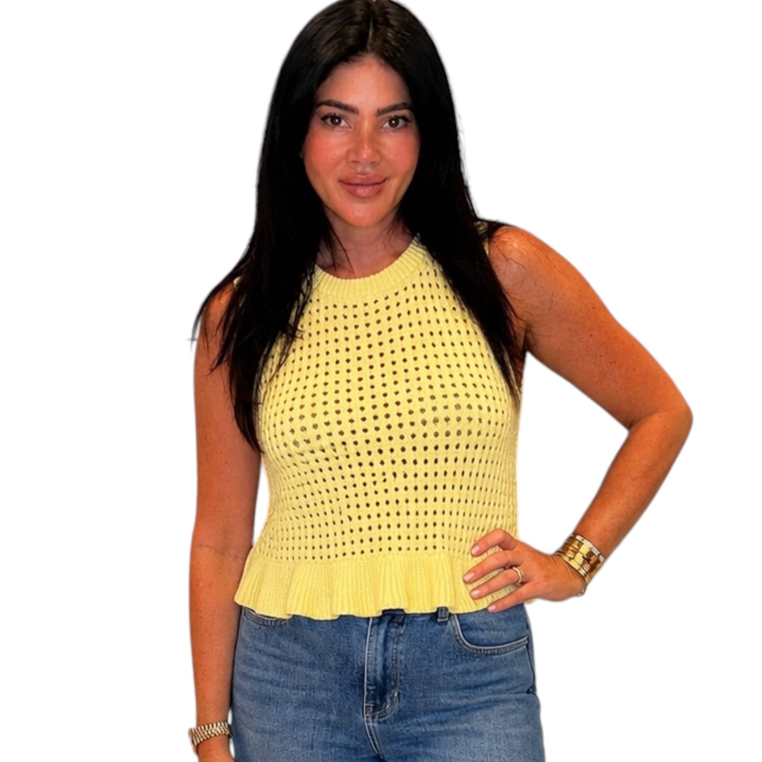 Woman wearing a yellow sleeveless top and blue jeans on a white background
