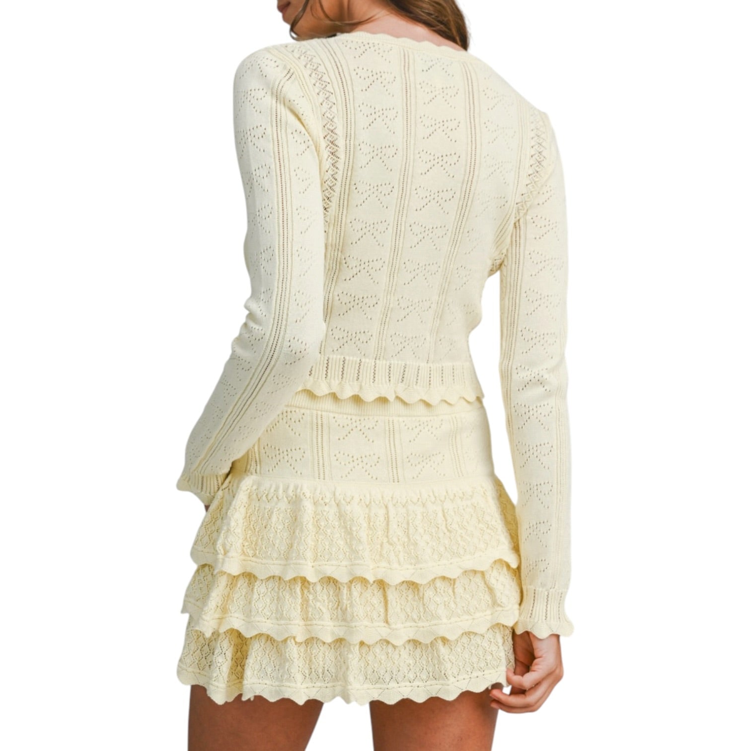 Woman wearing a lemon colored knitted set with a white background