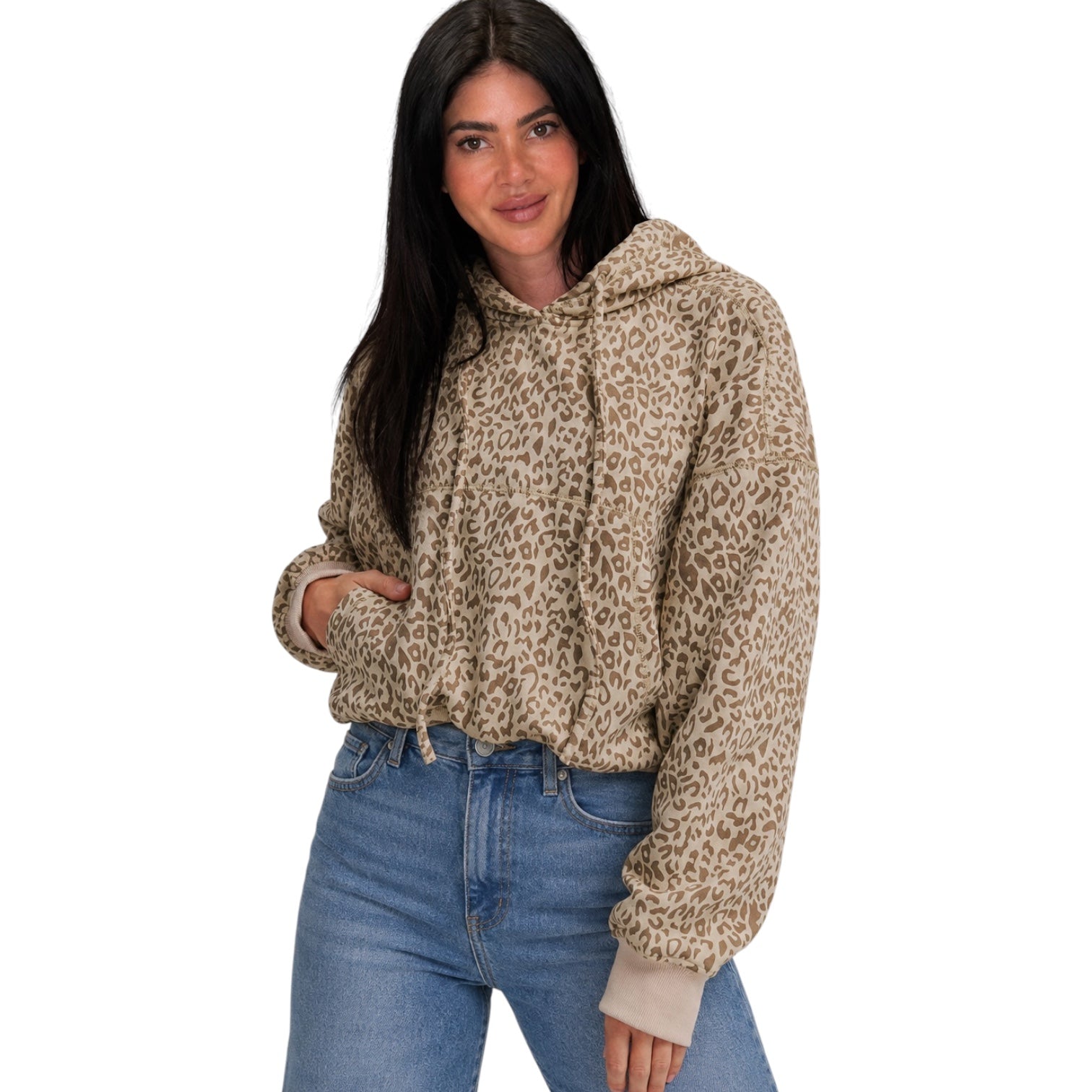 A woman wearing a beige and brown leopard-print hooded sweatshirt with light beige ribbed cuffs, paired with blue jeans, against a plain white background.