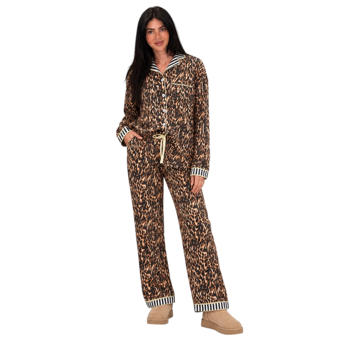 A woman modeling a matching two-piece pajama set with a brown and black leopard print, featuring striped trim on the collar, cuffs, and hem, paired with tan slip-on shoes against a plain white background.
