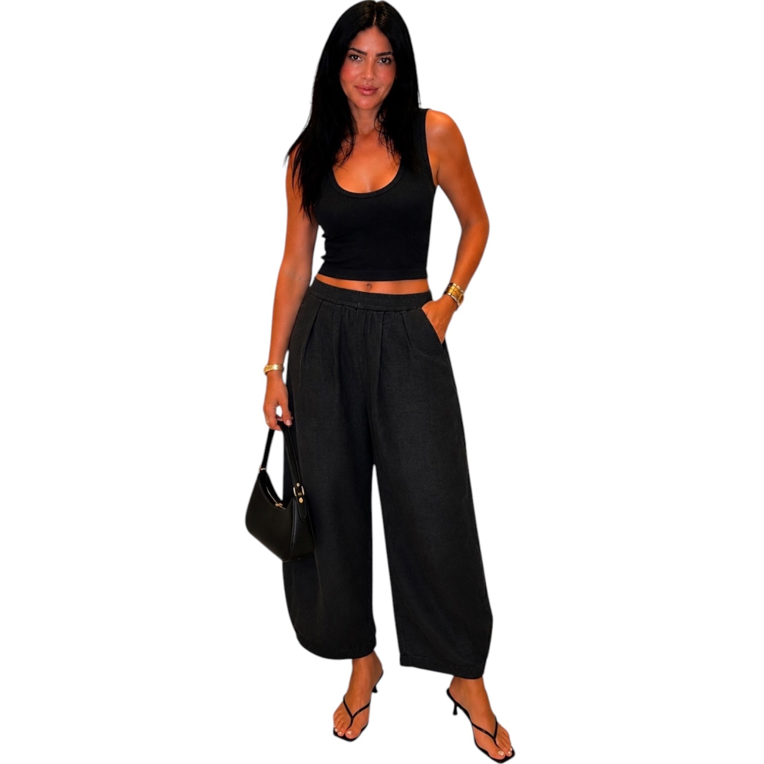 Woman wearing a black sleeveless top and wide-leg pants on a white background