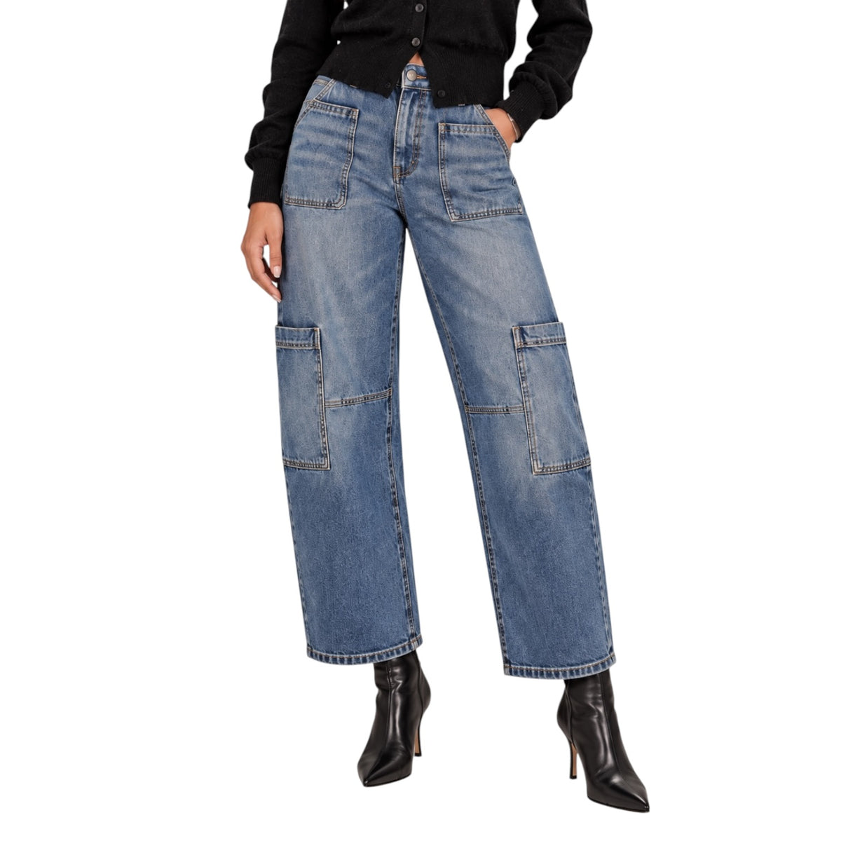 A model wearing a pair of wide-leg blue denim cargo pants with large patch pockets on the thighs and knees, styled with a black long-sleeve top and black pointed-toe heeled ankle boots against a plain white background.