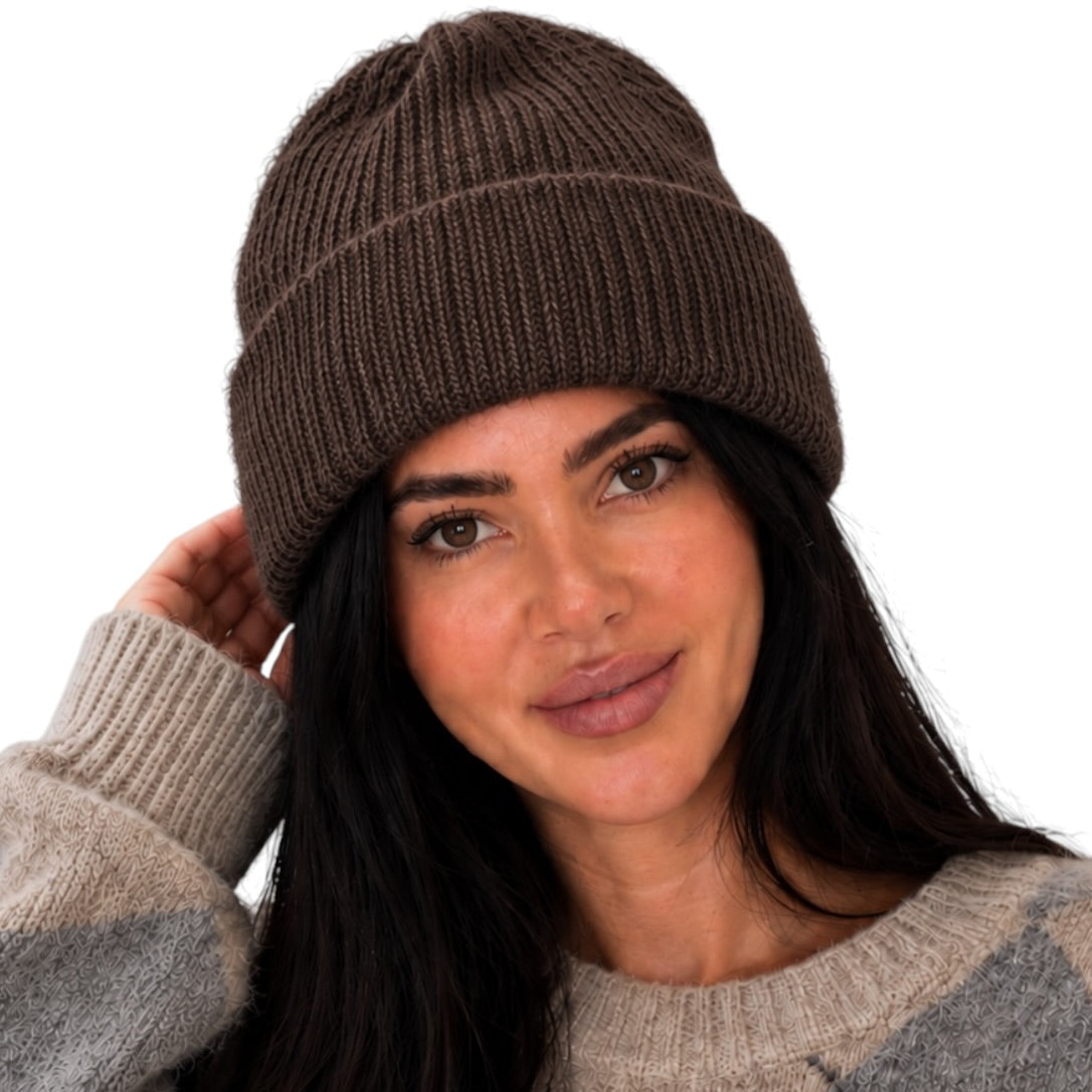 A woman wearing a dark brown ribbed knit beanie and a gray and beige argyle sweater, shown against a plain white background.