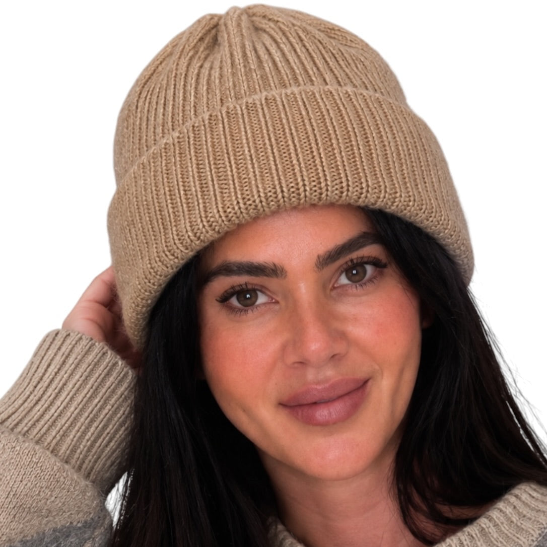 A woman wearing a beige ribbed knit beanie and a gray and beige argyle sweater, shown against a plain white background.