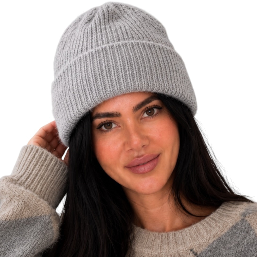 A woman wearing a light gray ribbed knit beanie and a beige and gray argyle sweater, shown against a plain white background.