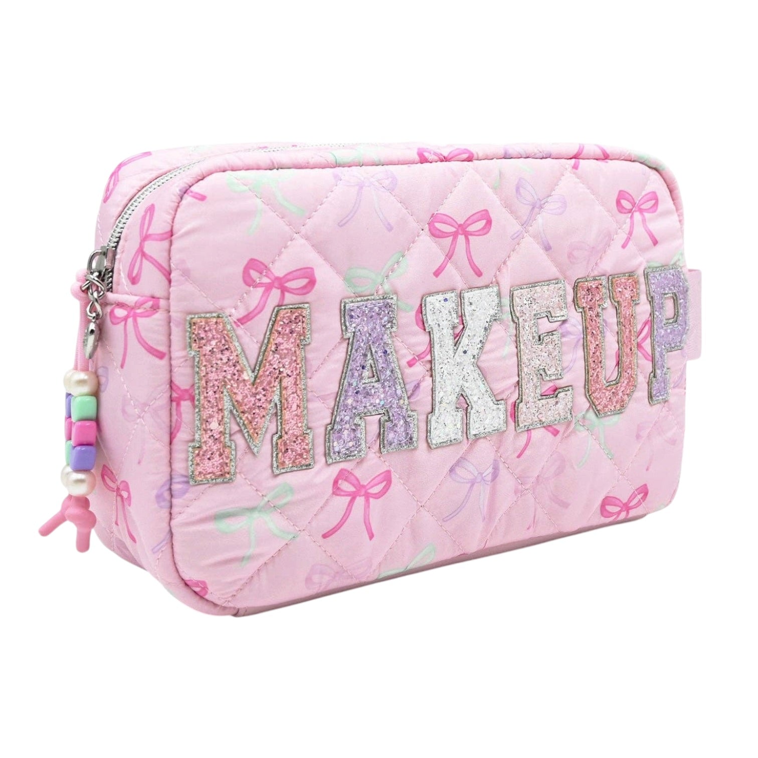 A pink quilted cosmetic pouch with 'MAKEUP' spelled out in glittery letters across the front, decorated with pink bow motifs and a colorful bead charm on the zipper pull.