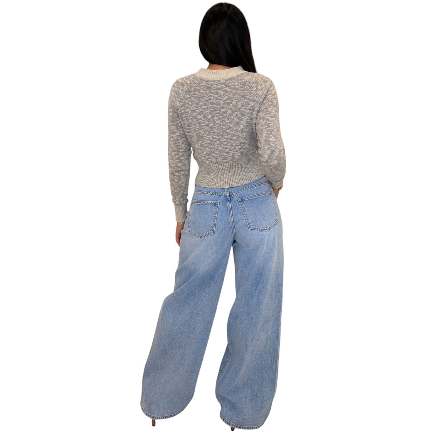 A woman shown from the back wearing a light gray marled knit long-sleeve crop top and wide-leg light blue denim jeans, set against a plain white background.