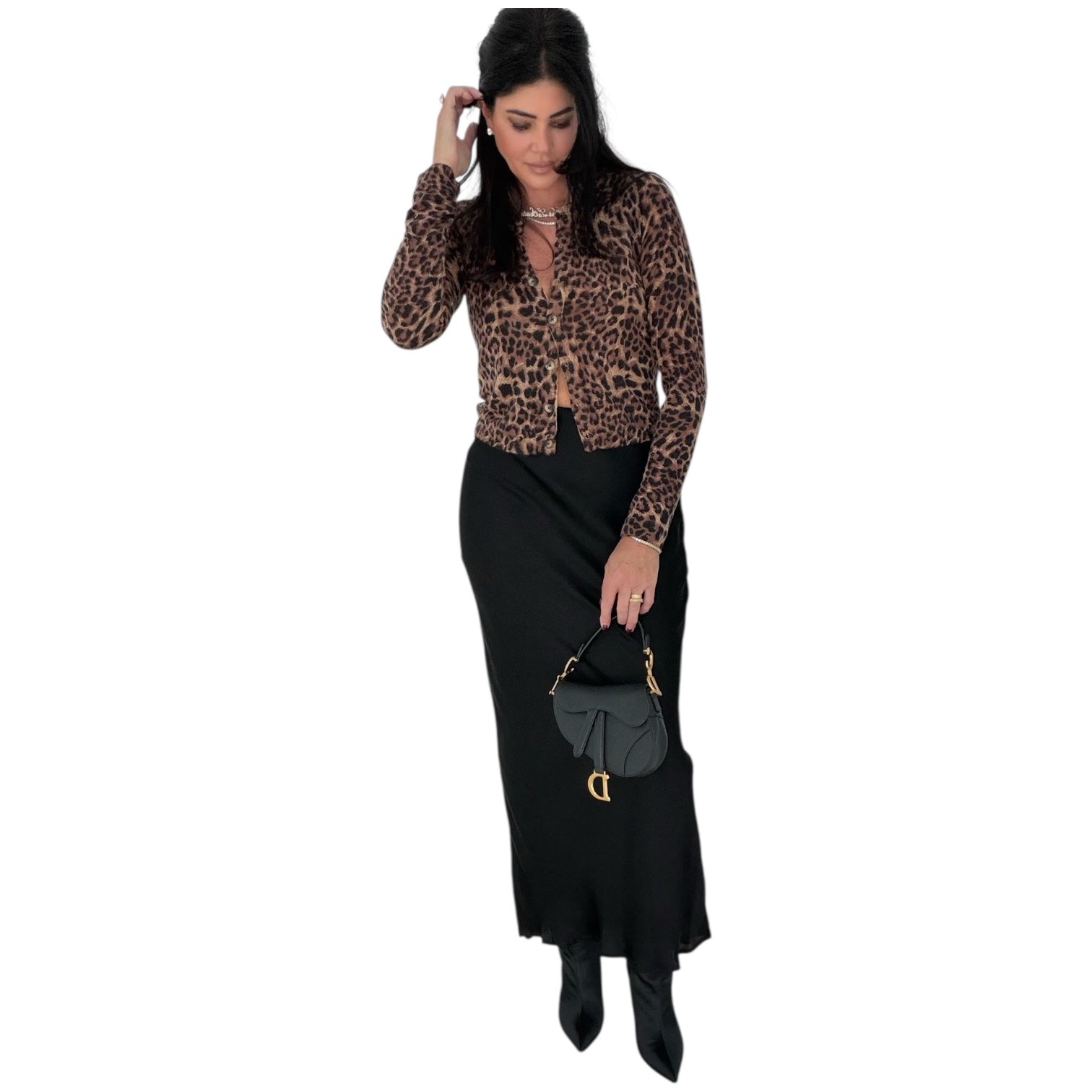Woman wearing a leopard print top and black skirt holding a black handbag on a white background
