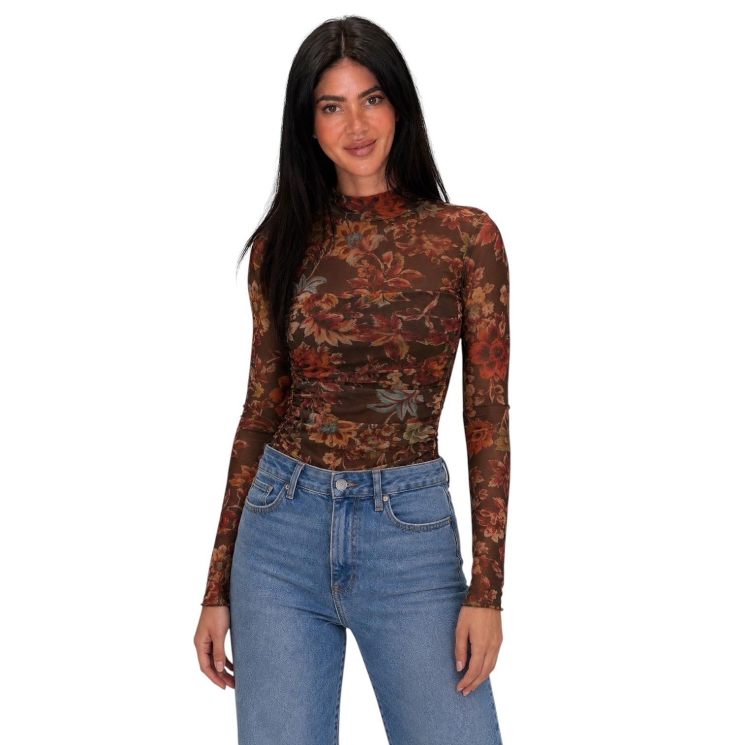A woman modeling a long-sleeve mock neck bodysuit with a brown, rust, and orange floral pattern, paired with blue jeans, against a plain white background.