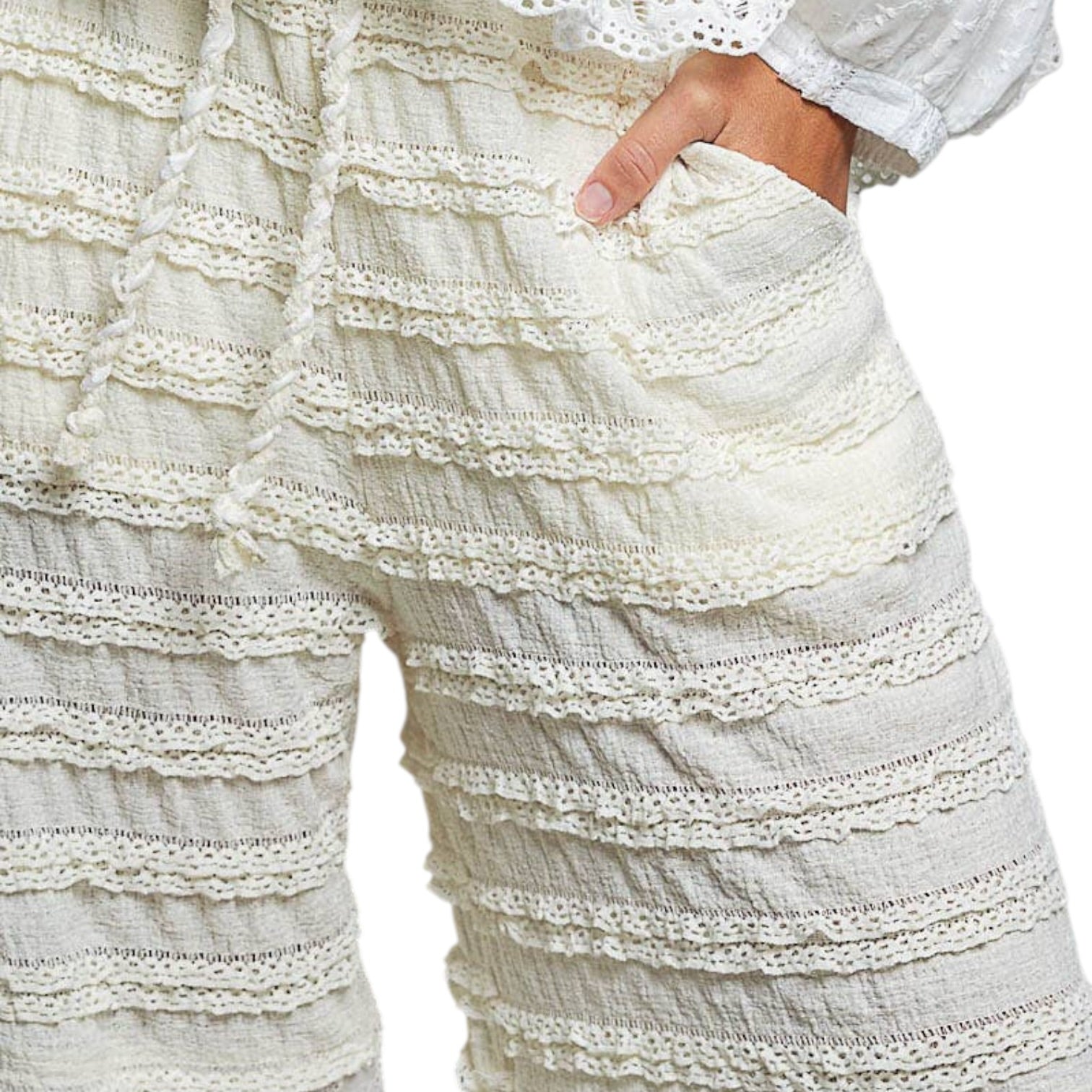 Close-up of a person wearing cream-colored lace-trimmed pants on a white background