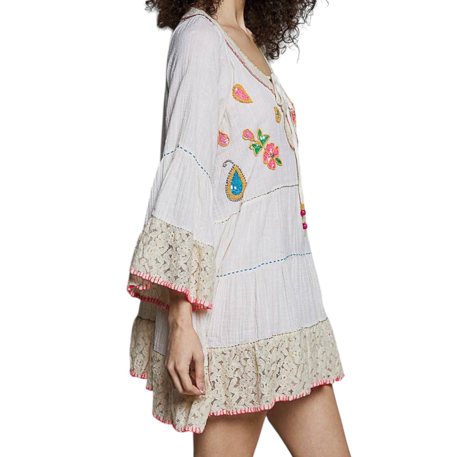 Woman wearing a white dress with colorful embroidery and lace details on a white background