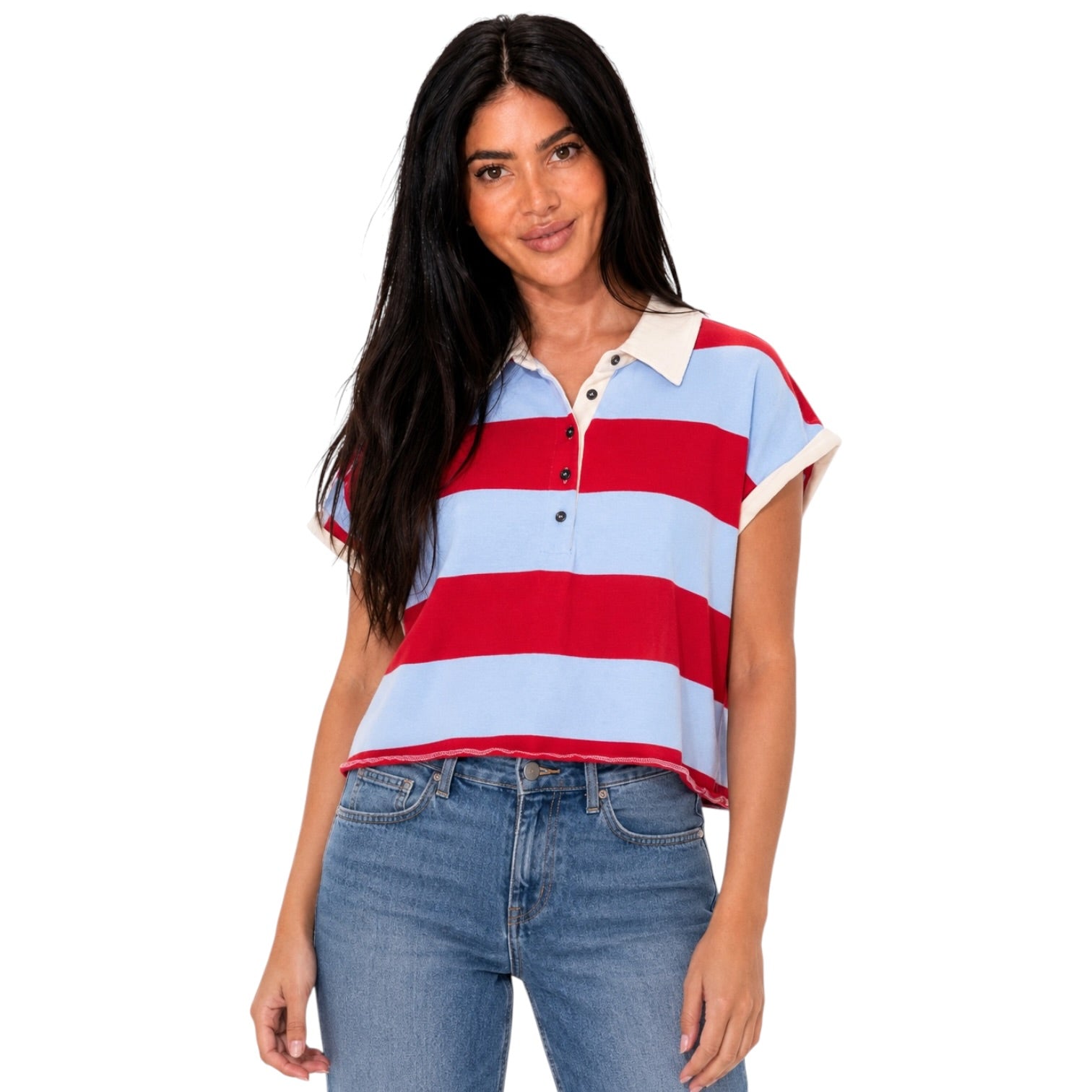 A woman modeling a short-sleeve polo shirt with horizontal red and light blue stripes, featuring a cream collar and button placket, paired with blue jeans against a plain white background.