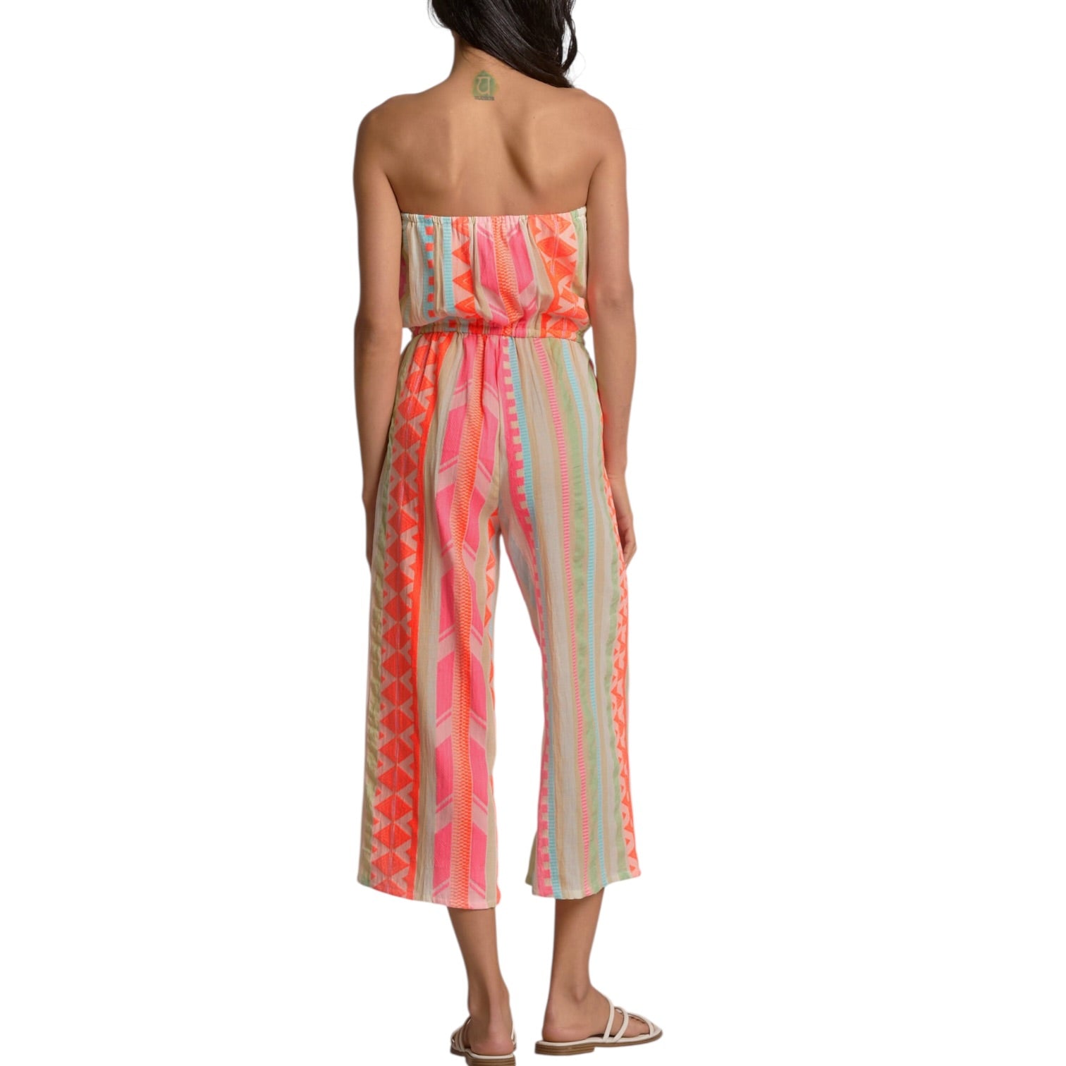 Woman wearing a strapless, patterned jumpsuit on a white background