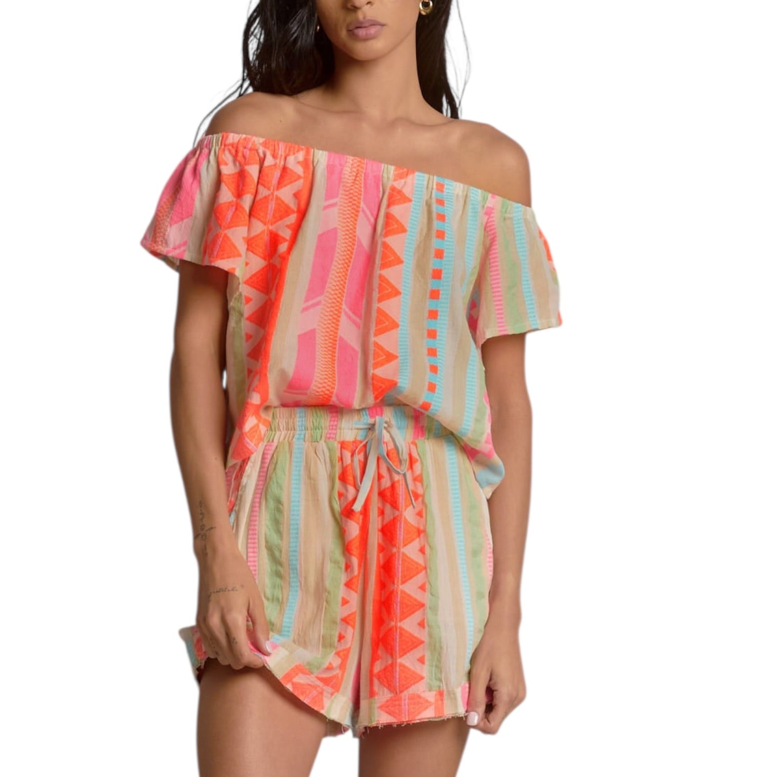 Woman wearing a colorful off-shoulder romper on a white background