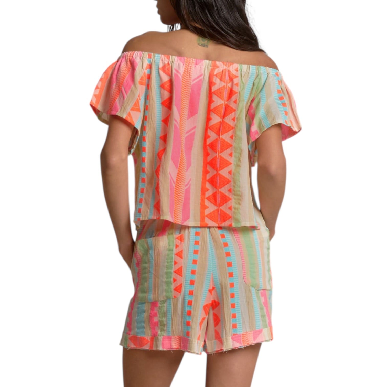 Woman wearing a colorful off-shoulder dress with geometric pattern on a white background