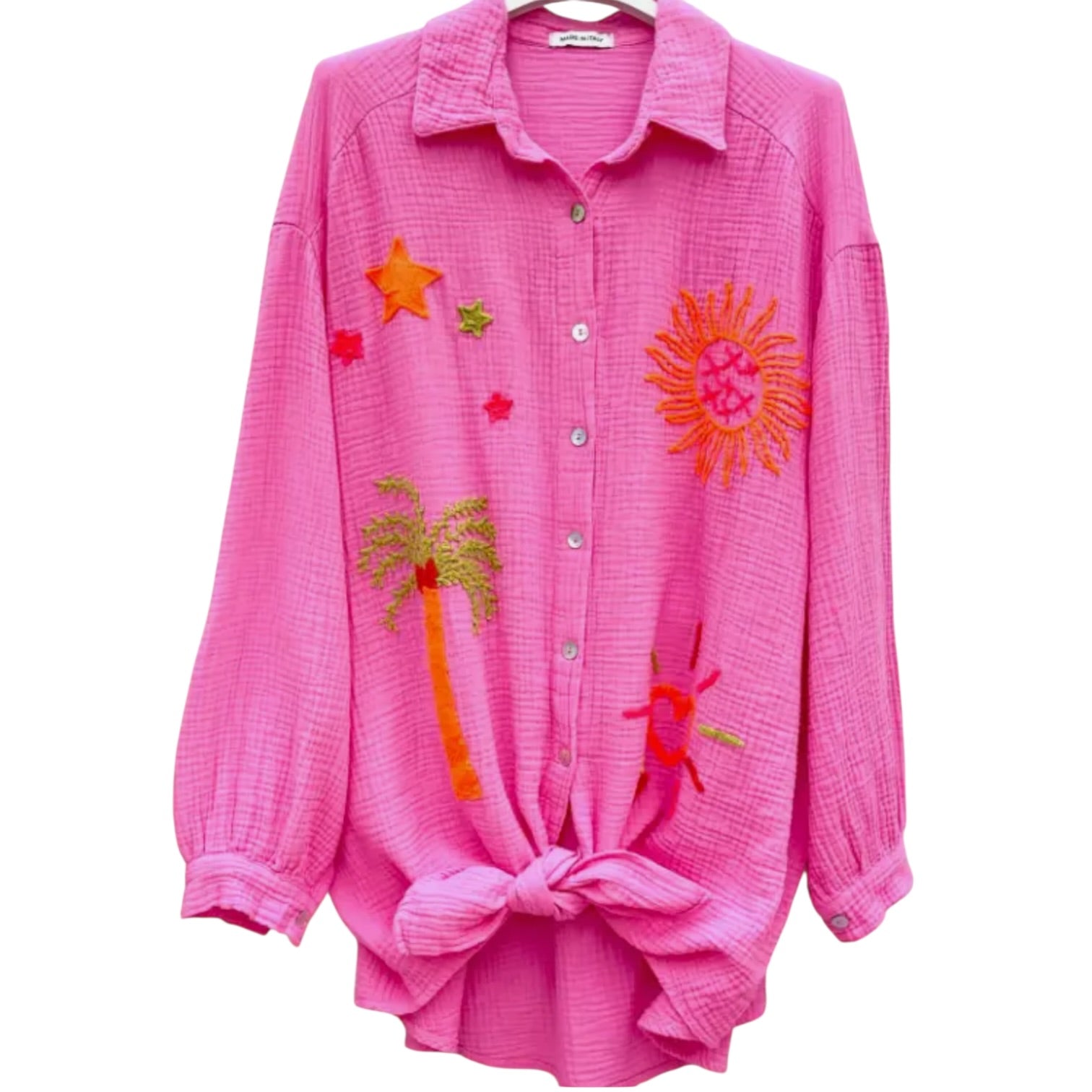 Pink shirt with colorful embroidered designs on a white background