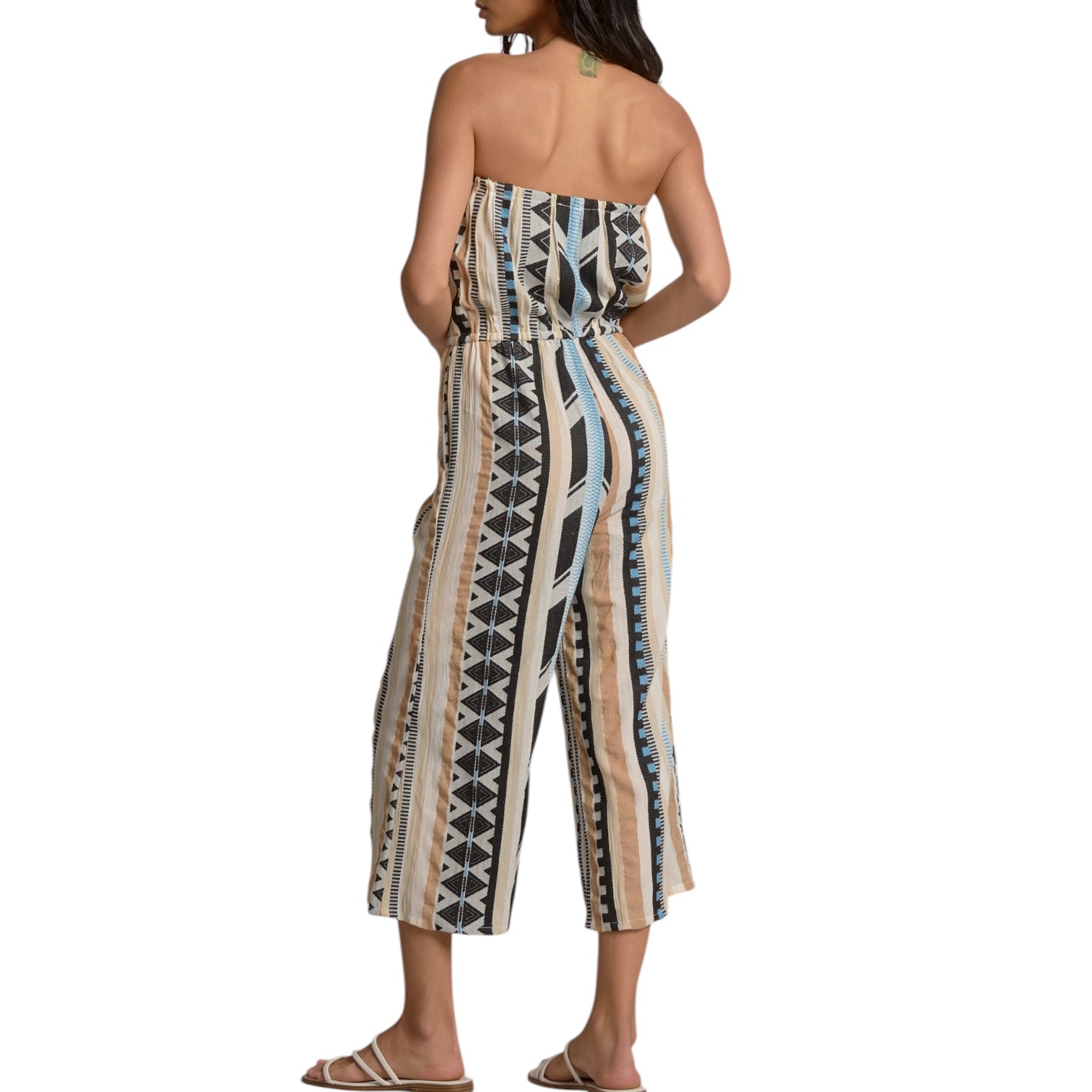 Woman wearing a strapless, patterned jumpsuit on a white background