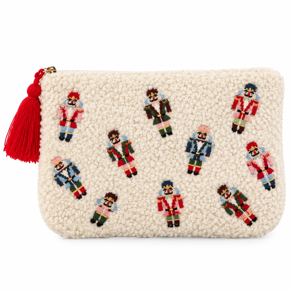 An off-white sherpa zip pouch decorated with embroidered nutcracker figures in red, blue, green, and pink, featuring a red tassel zipper pull on a white background.