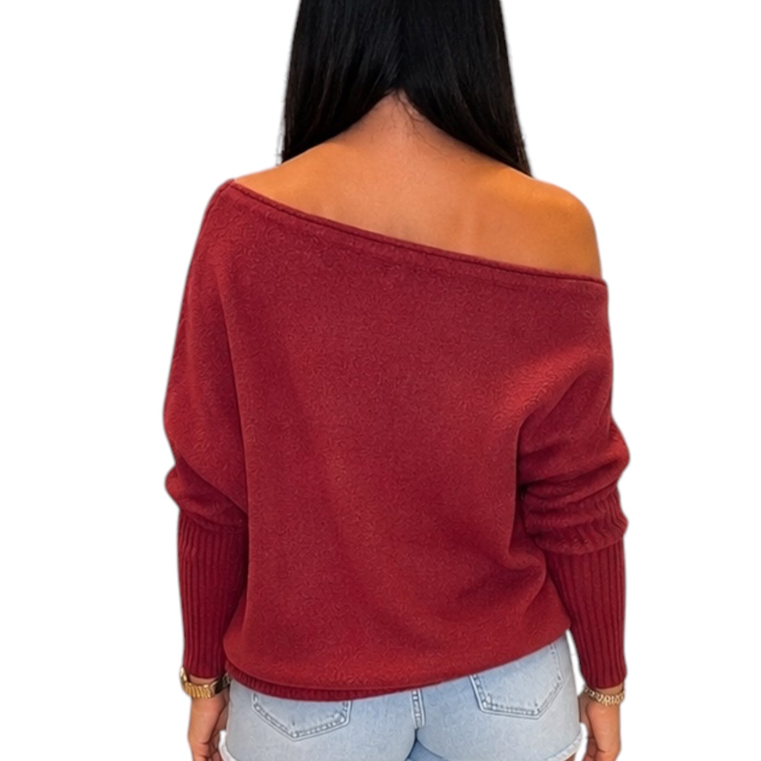 A woman shown from the back wearing a deep red off-the-shoulder knit sweater and light blue jeans against a plain white background.